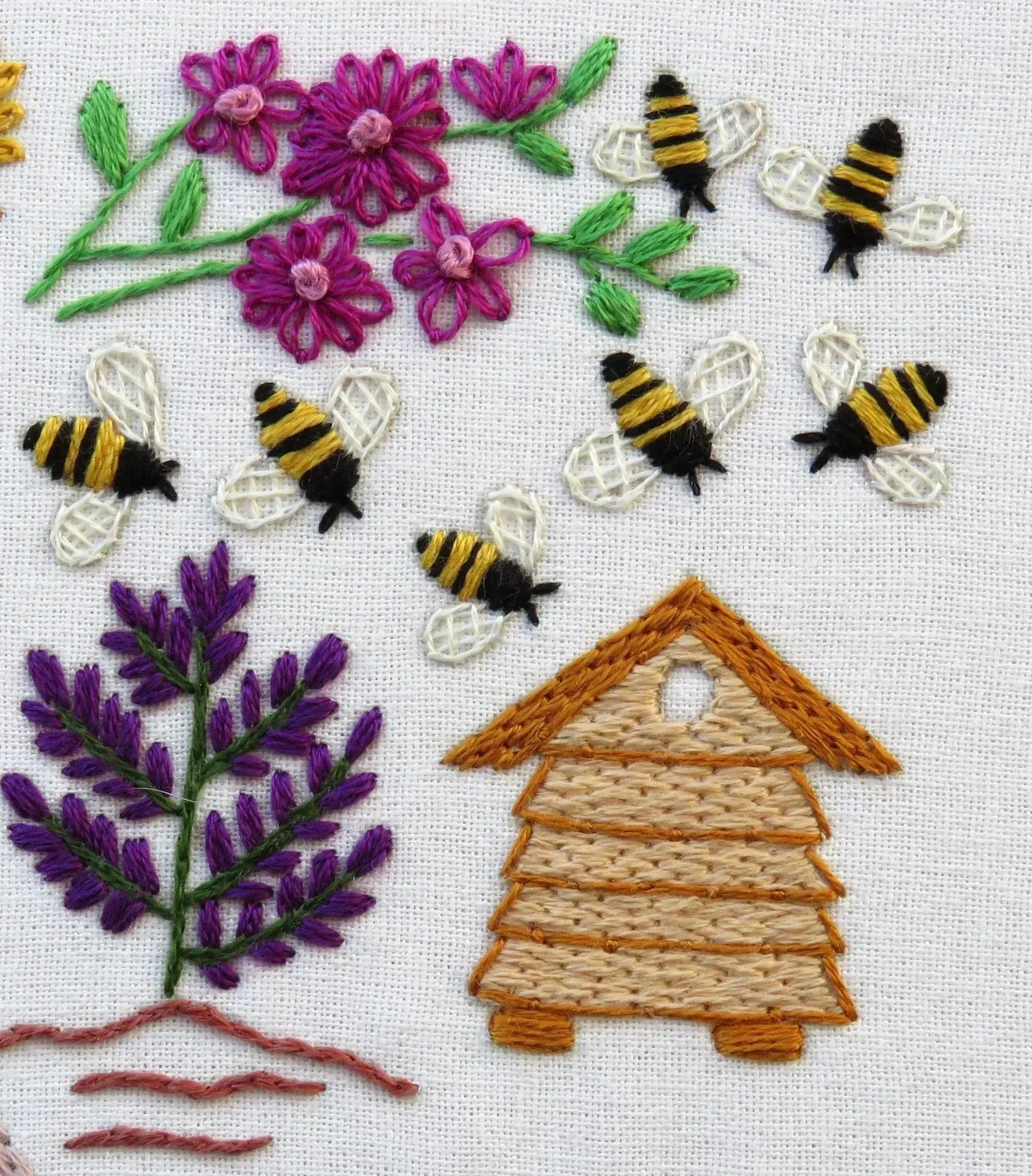 Embroidery design with bees, flowers, and a beehive on a white background