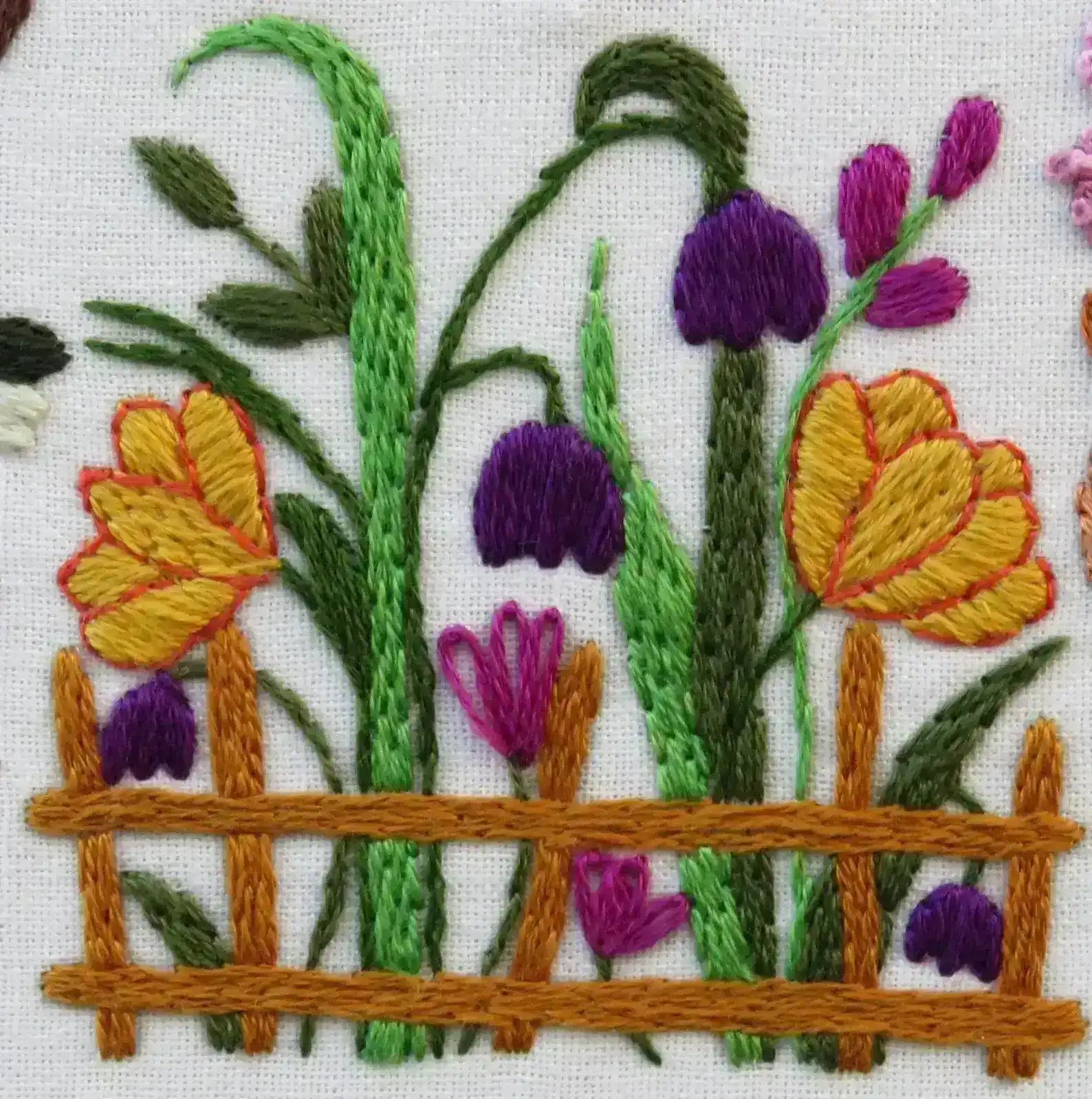 Embroidered design of flowers and a fence on a white background
