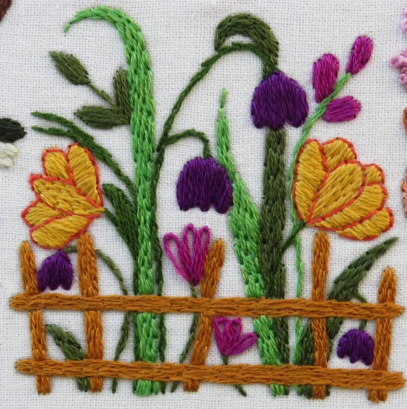 Embroidered design of flowers and a fence on a white background