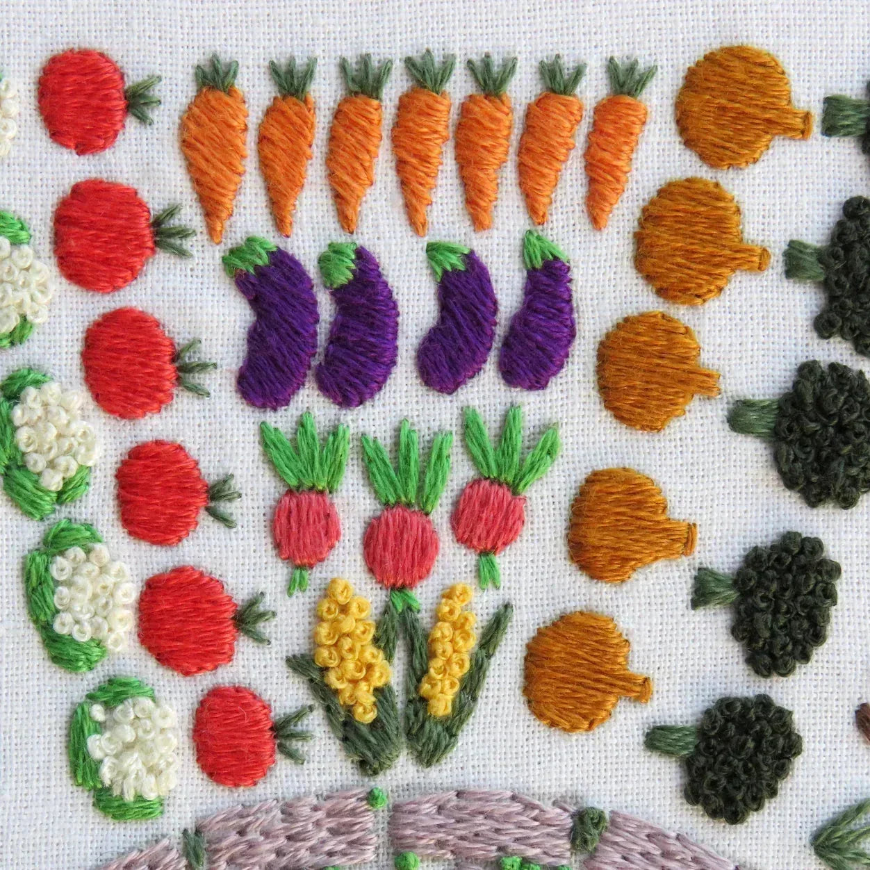 Embroidered vegetables including carrots, eggplants, and tomatoes on a white background