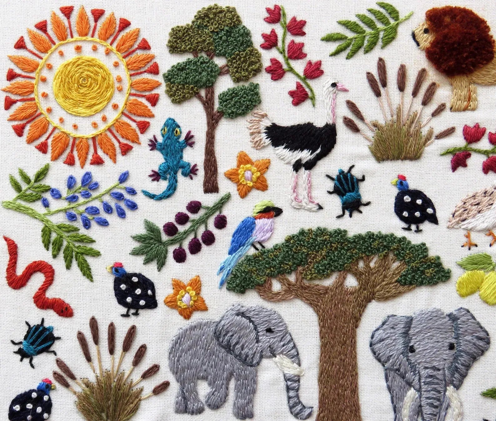 Embroidered scene with animals, trees, and flowers on a white background