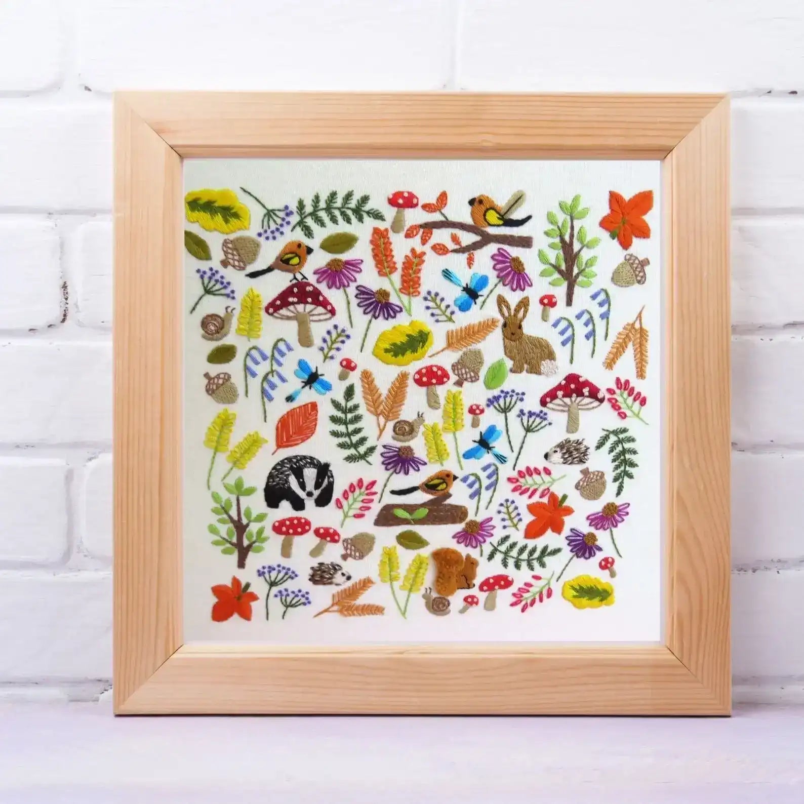 Framed artwork with colorful nature-themed design on a white brick wall background