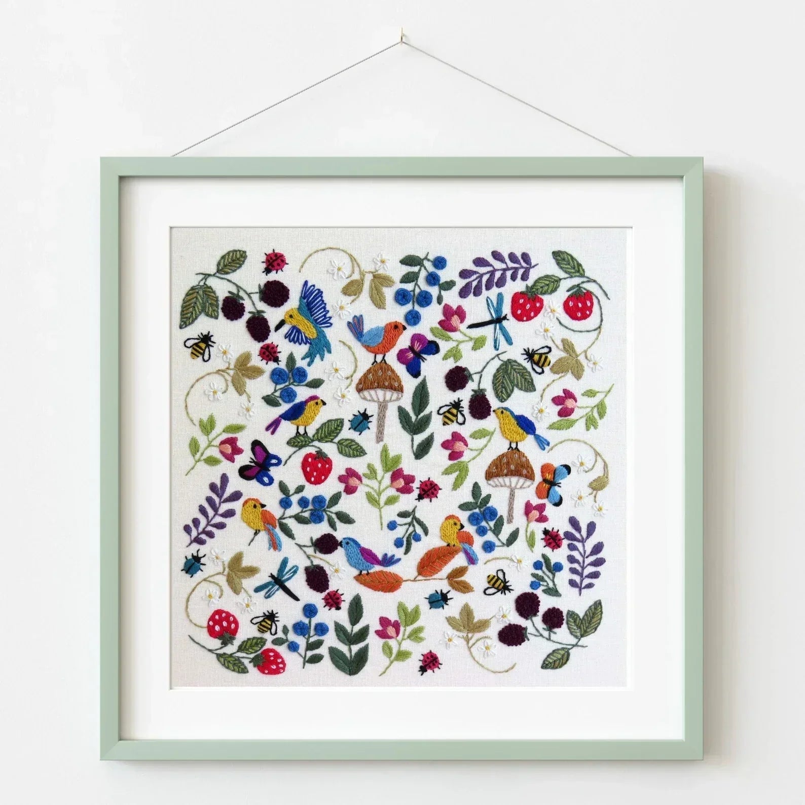 Framed artwork with colorful birds, flowers, and butterflies on a white background