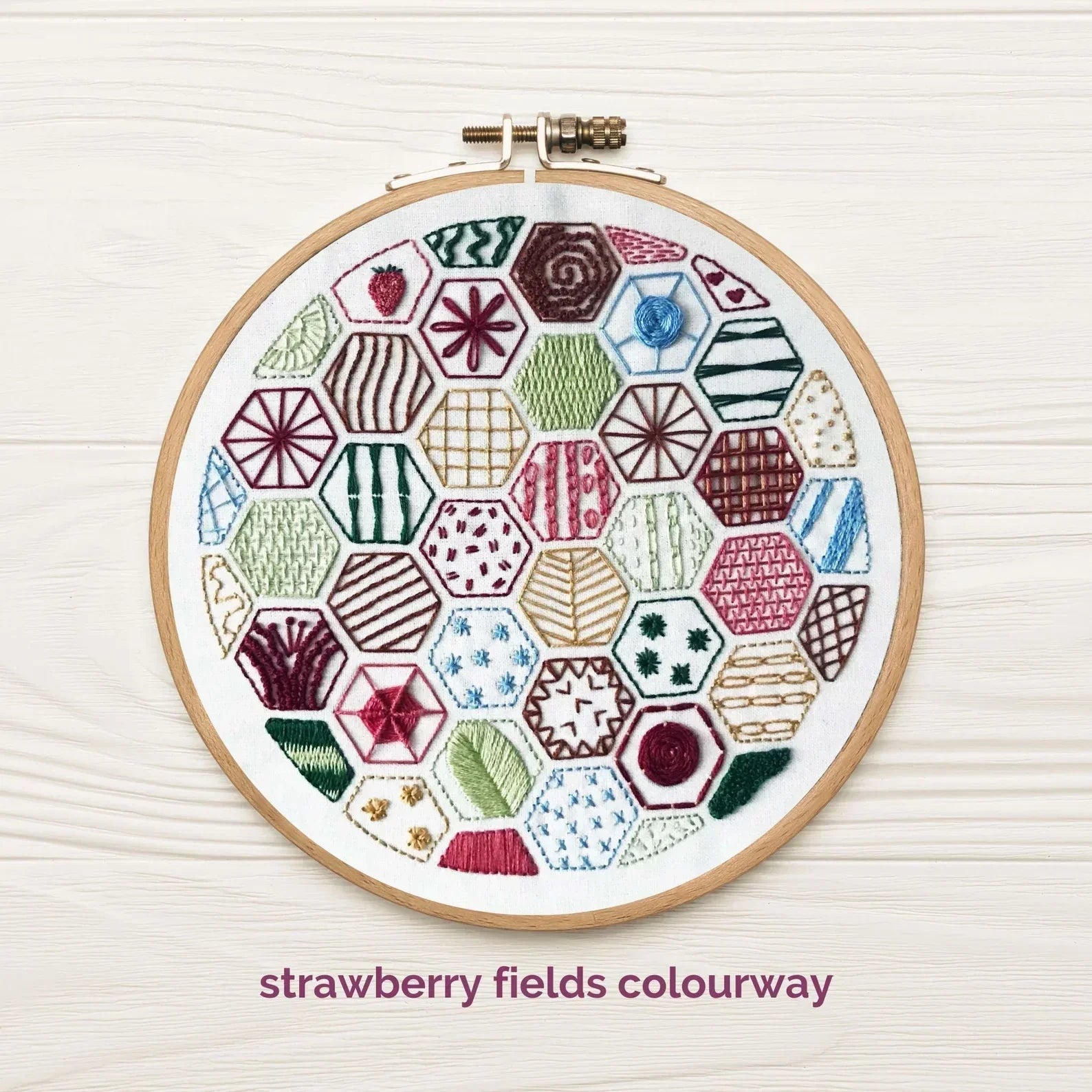 Embroidery hoop with colorful geometric pattern on a white background, labeled 'strawberry fields colourway'.