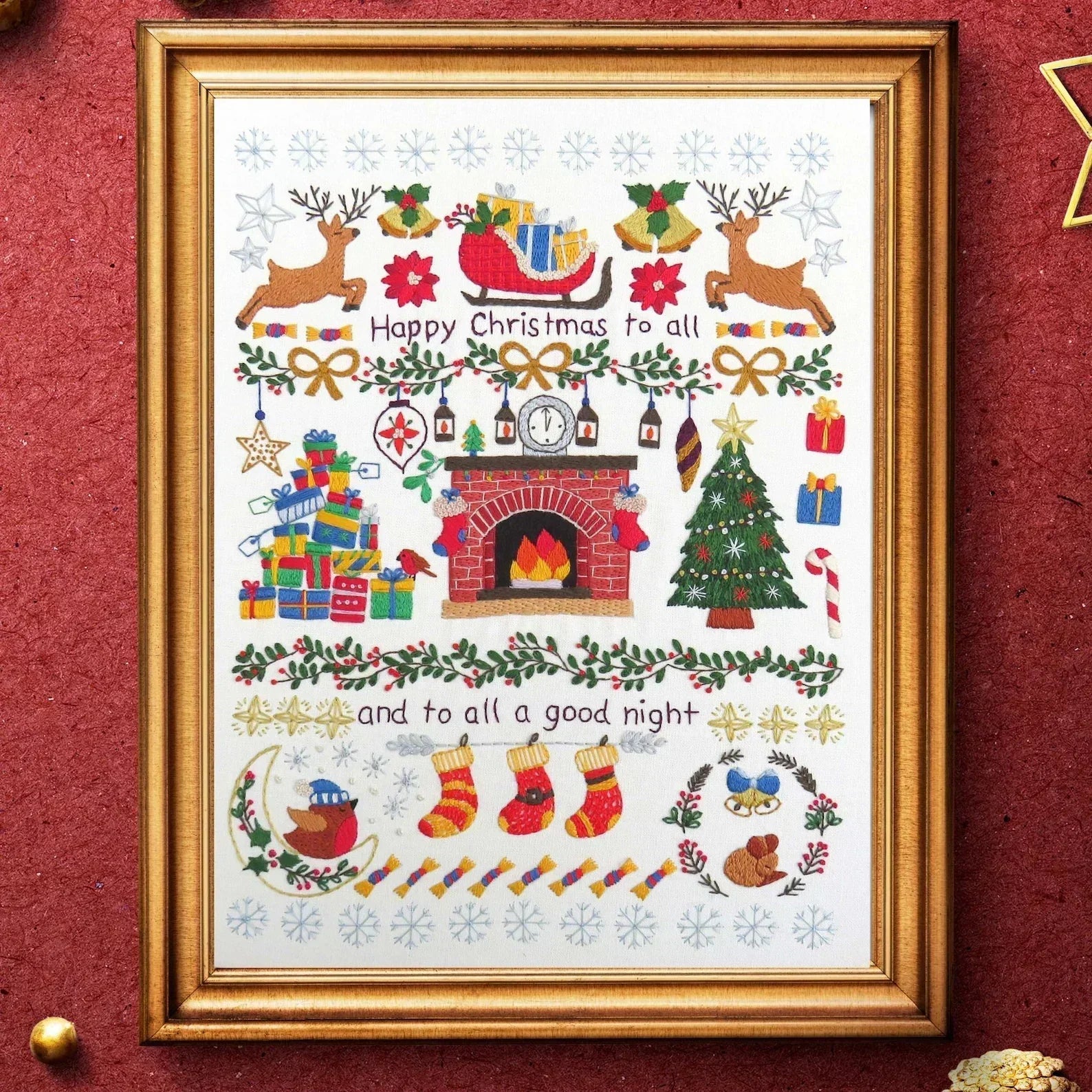 Framed Christmas-themed artwork with reindeer, Santa's sleigh, fireplace, and stockings on a red background.