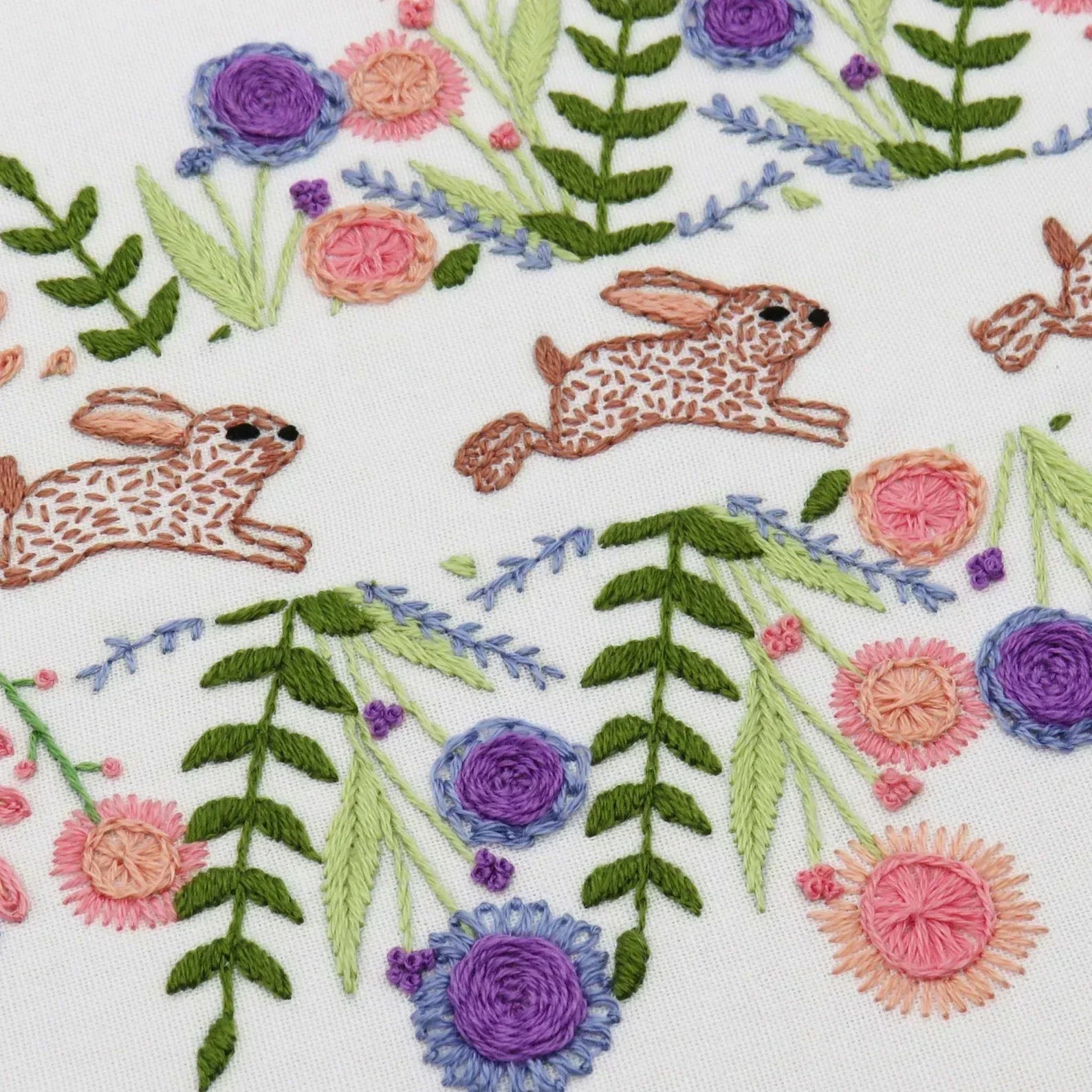 Embroidered design with rabbits and flowers on a white background