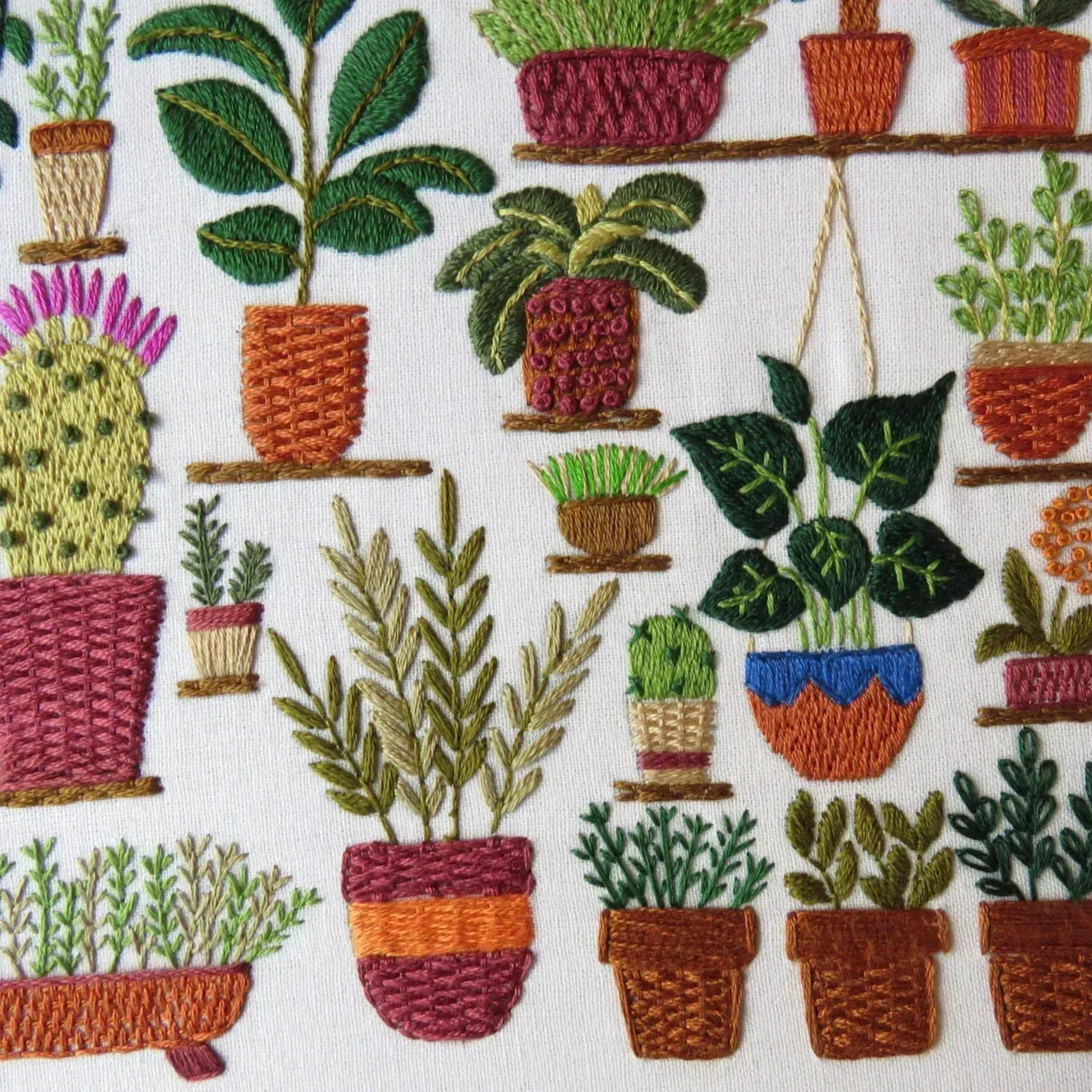 Embroidered pattern of various potted plants on a white background