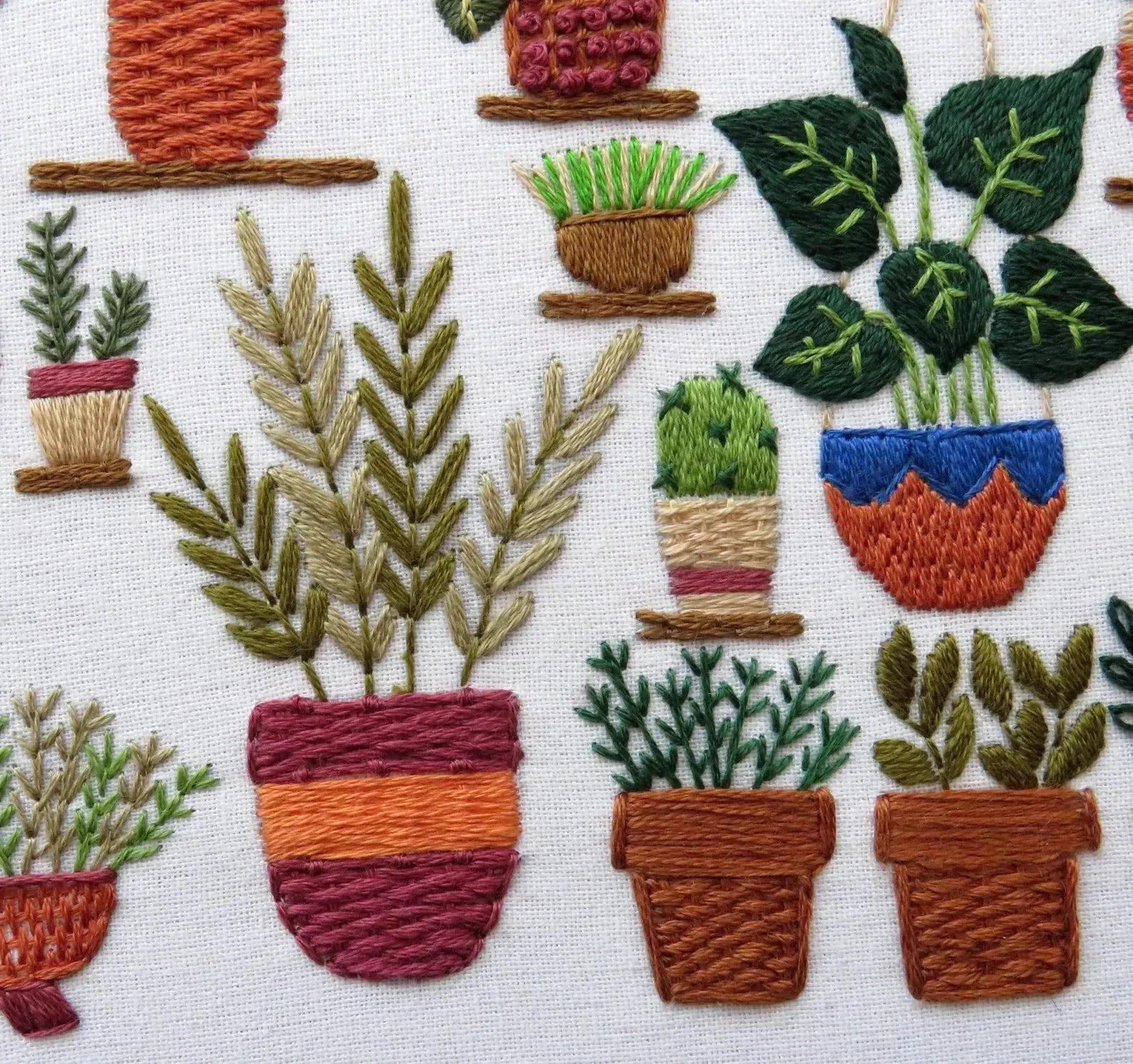 Embroidered pattern of various potted plants on a white background