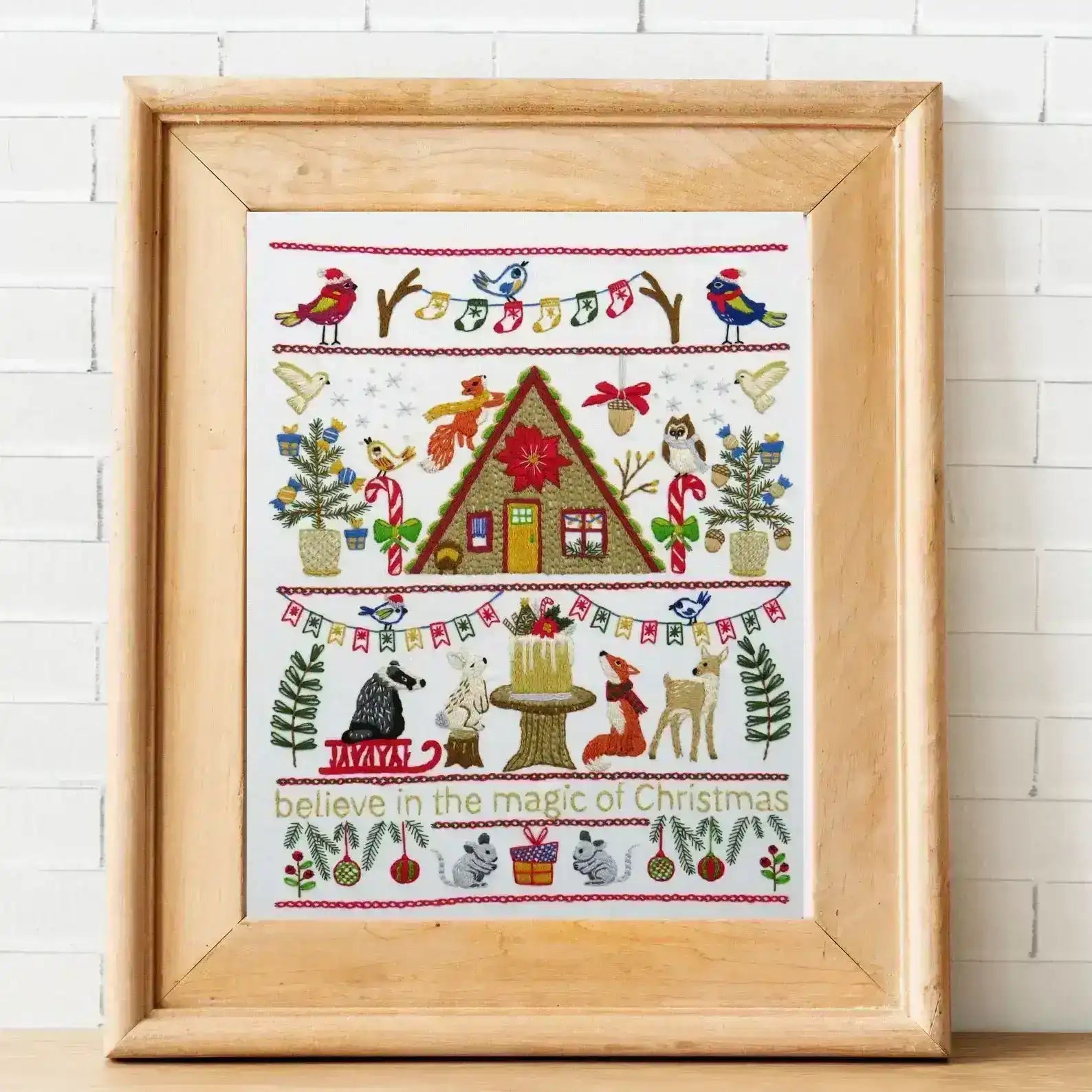 Framed cross-stitched artwork with Christmas-themed design on a white background