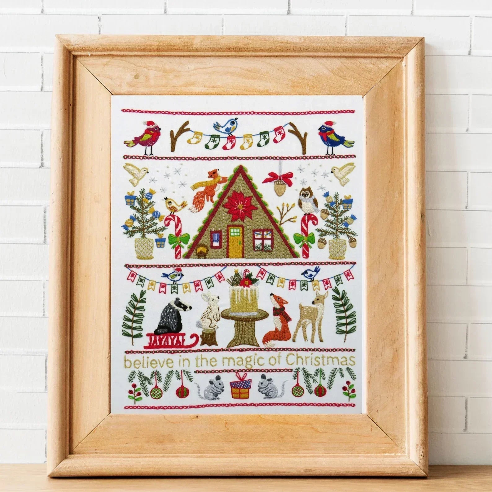 Framed cross-stitched artwork with Christmas-themed design on a white background