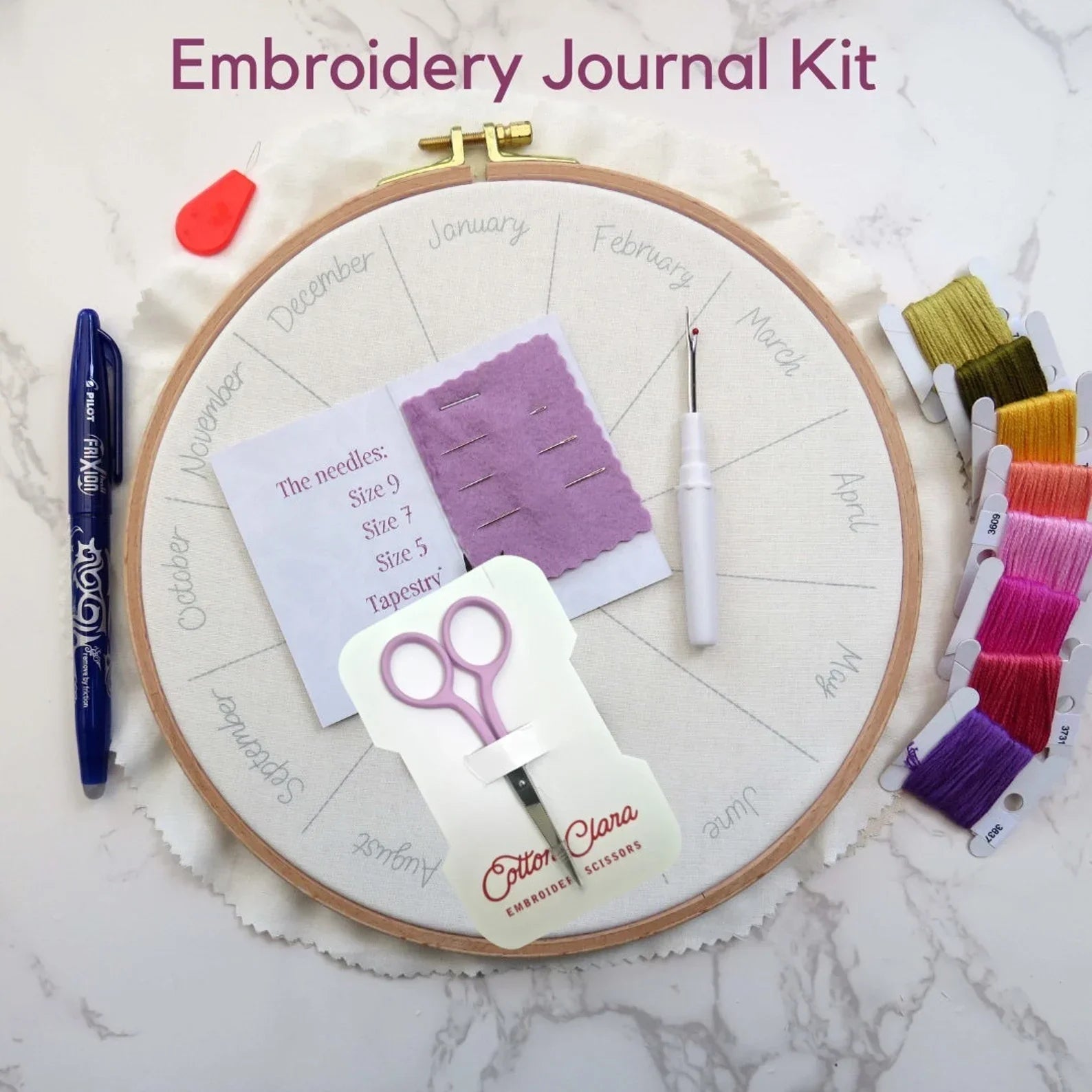 Embroidery Journal Kit with hoop, scissors, threads, and tools on a marble surface