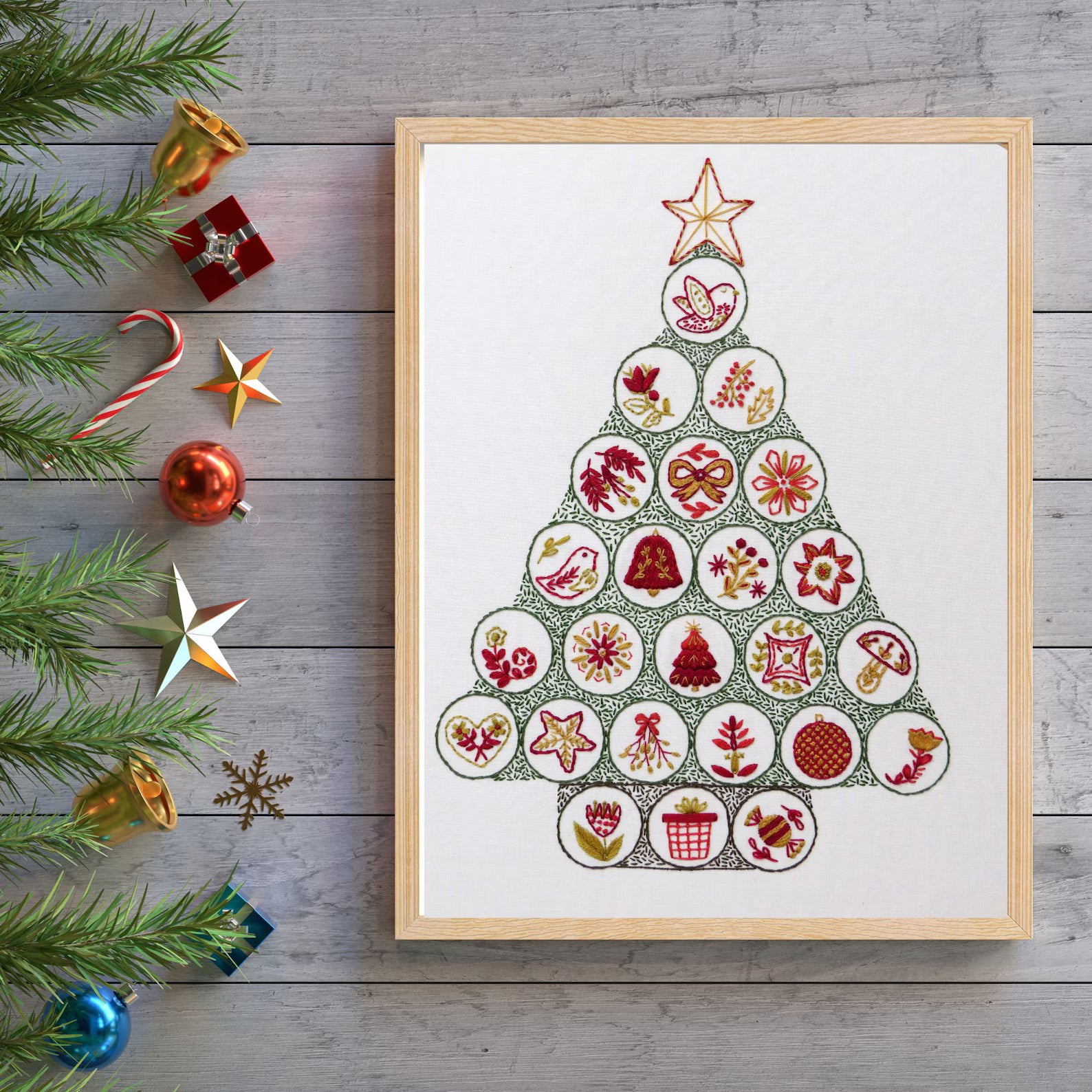 Framed Christmas tree art print with decorative elements on a wooden surface.