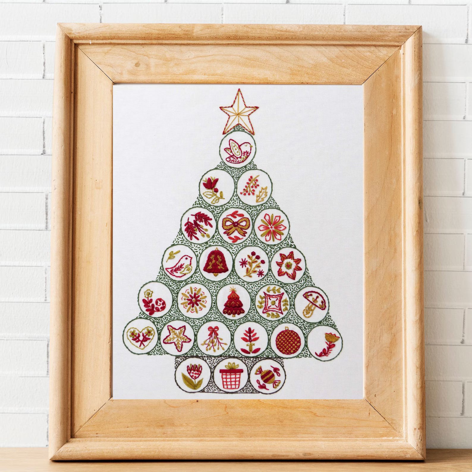 Framed artwork of a Christmas tree made from circular cutouts on a white background