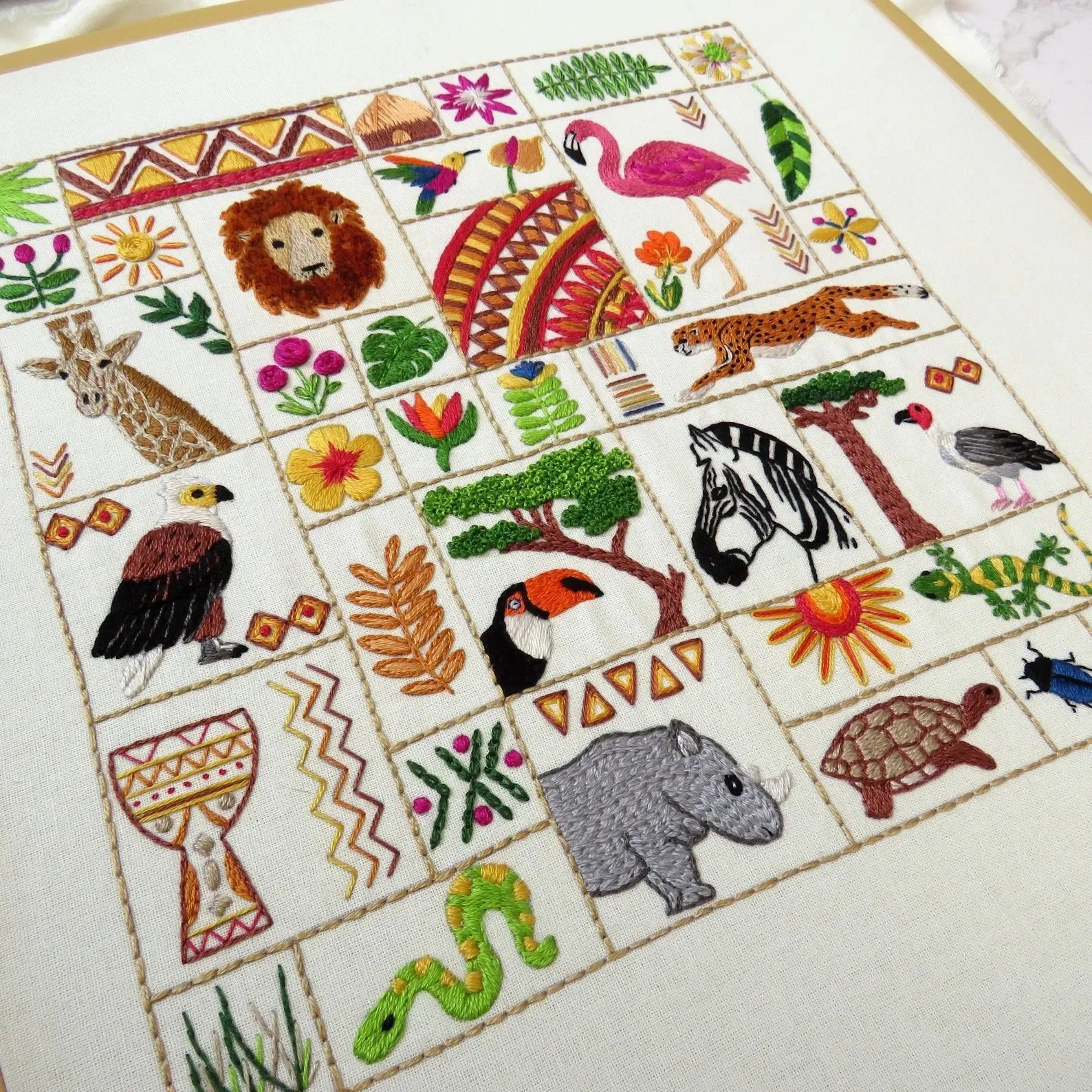Embroidered panel with various animals and patterns on a white background