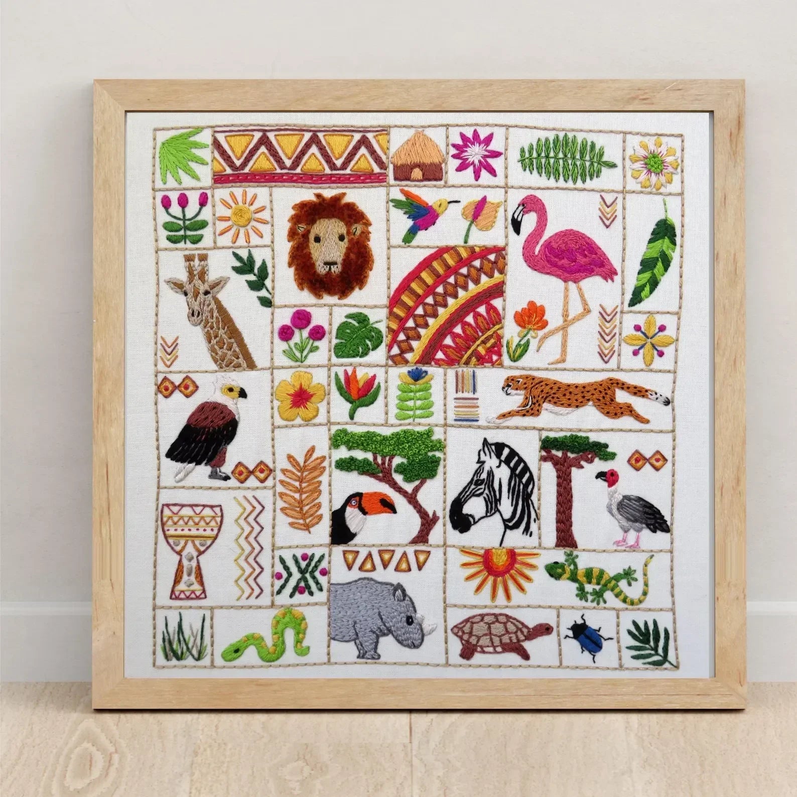 Framed embroidery with various animals and patterns on a white background