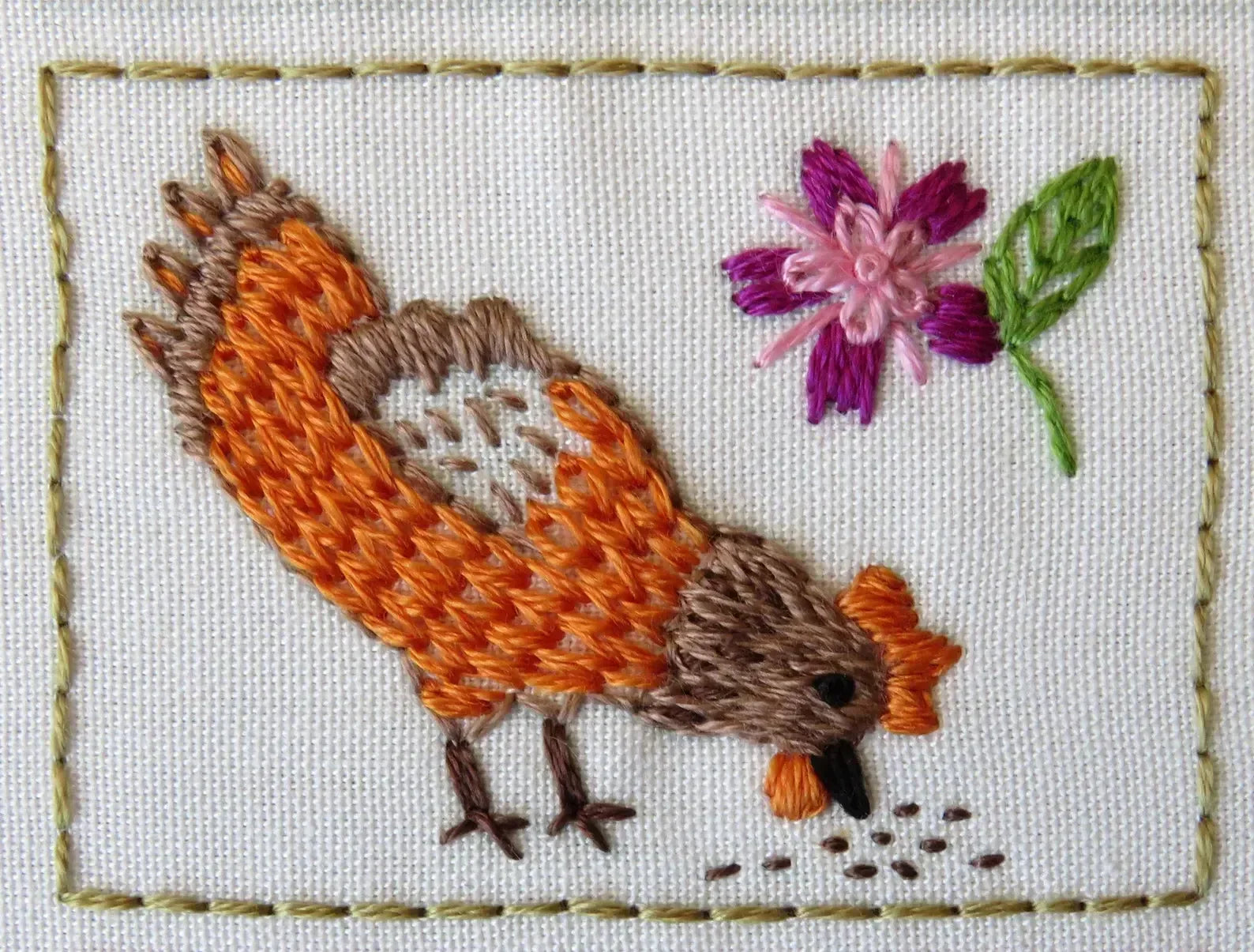 Embroidered design of a bird and flower on fabric