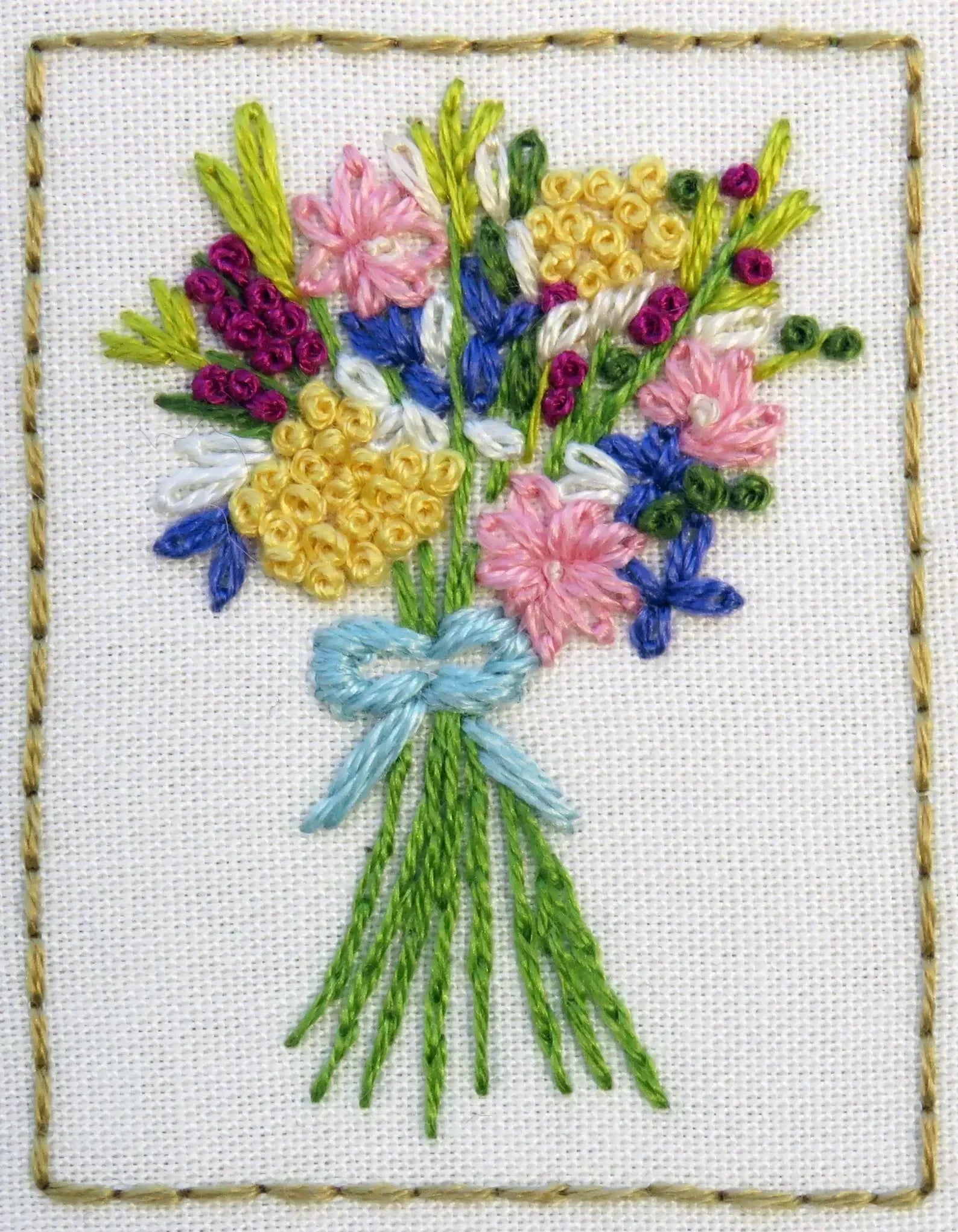 Embroidered bouquet of flowers with a blue bow on a white background