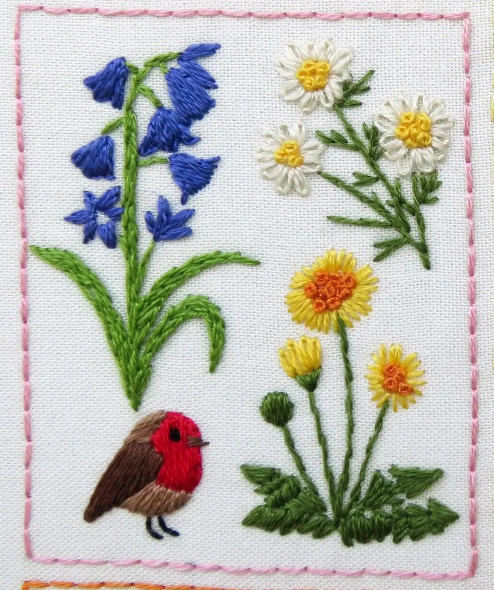 Embroidered design of a red robin among flowers on a white background