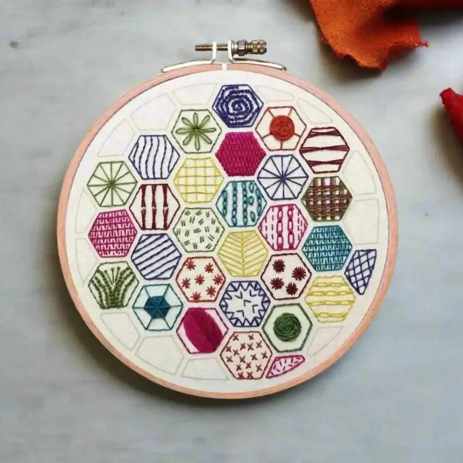 Embroidery hoop with colorful geometric pattern on a light background