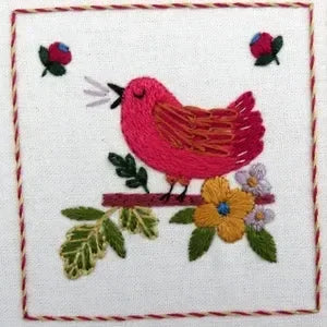 Embroidered patch with a pink bird and flowers on a white background