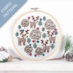 Embroidery hoop with deer and tree pattern on a white background