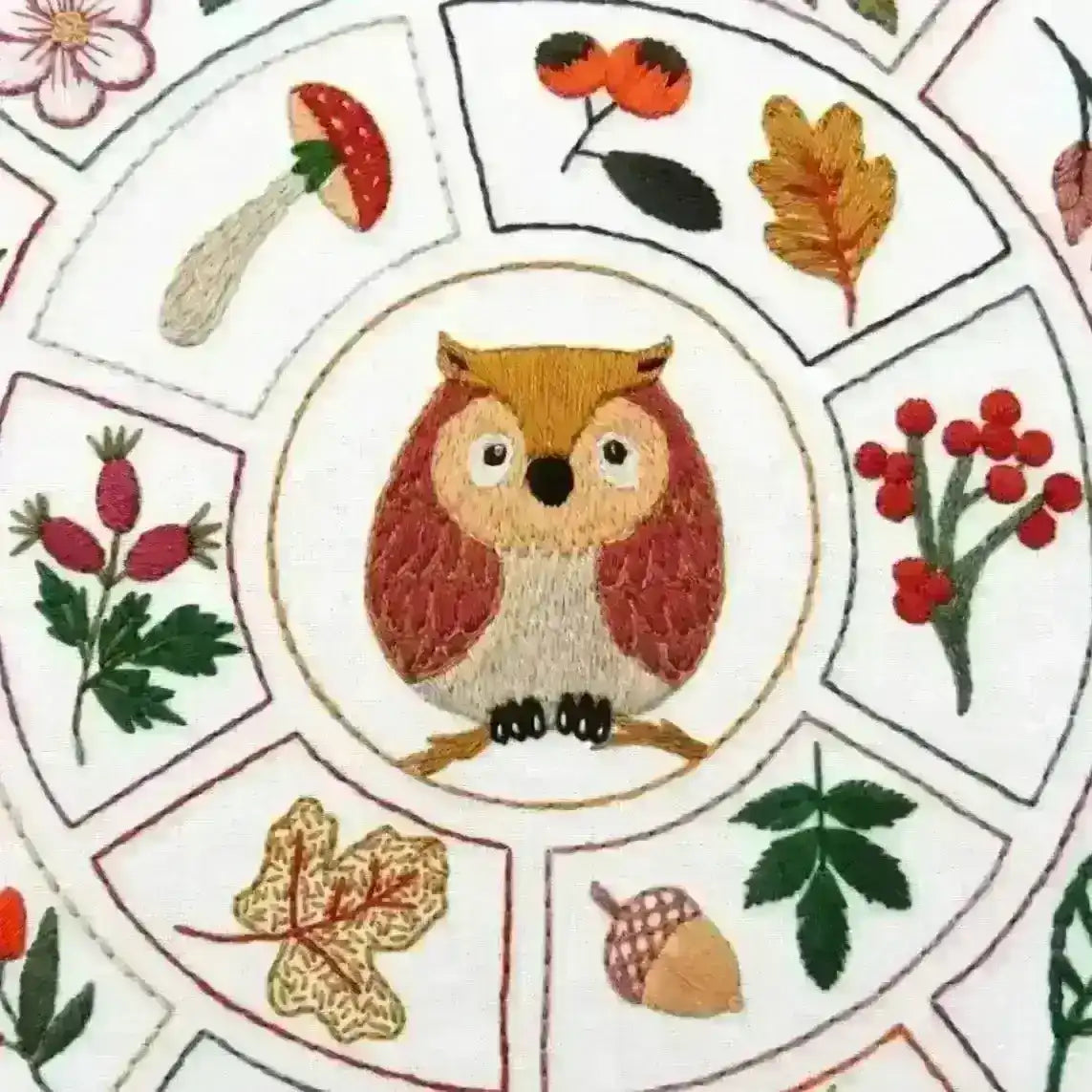 Embroidered design with an owl surrounded by leaves, berries, and mushrooms on a circular pattern.