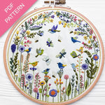 Embroidery hoop with floral and bird design on a white background