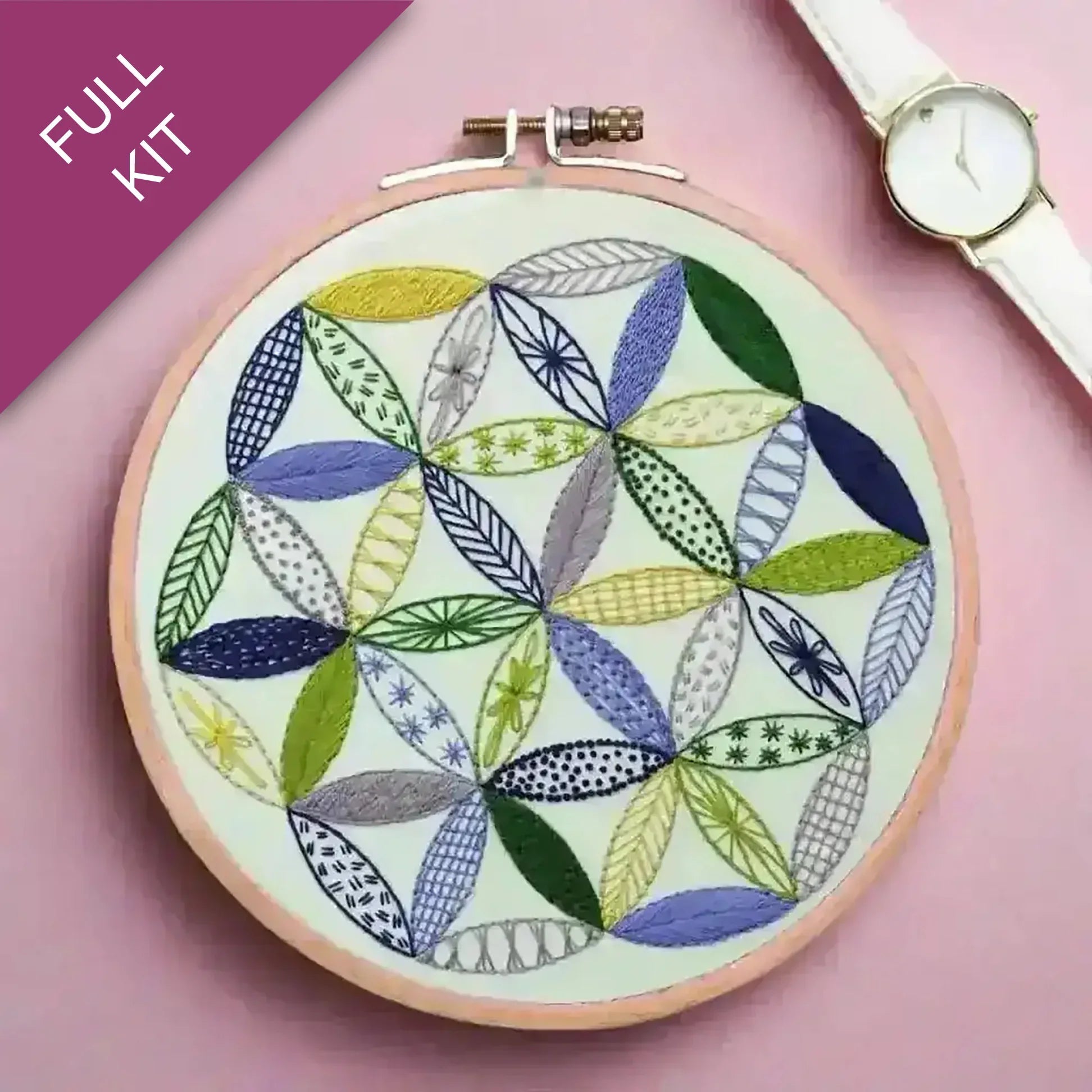 Embroidery hoop with colorful leaf pattern on a pink background, watch visible.