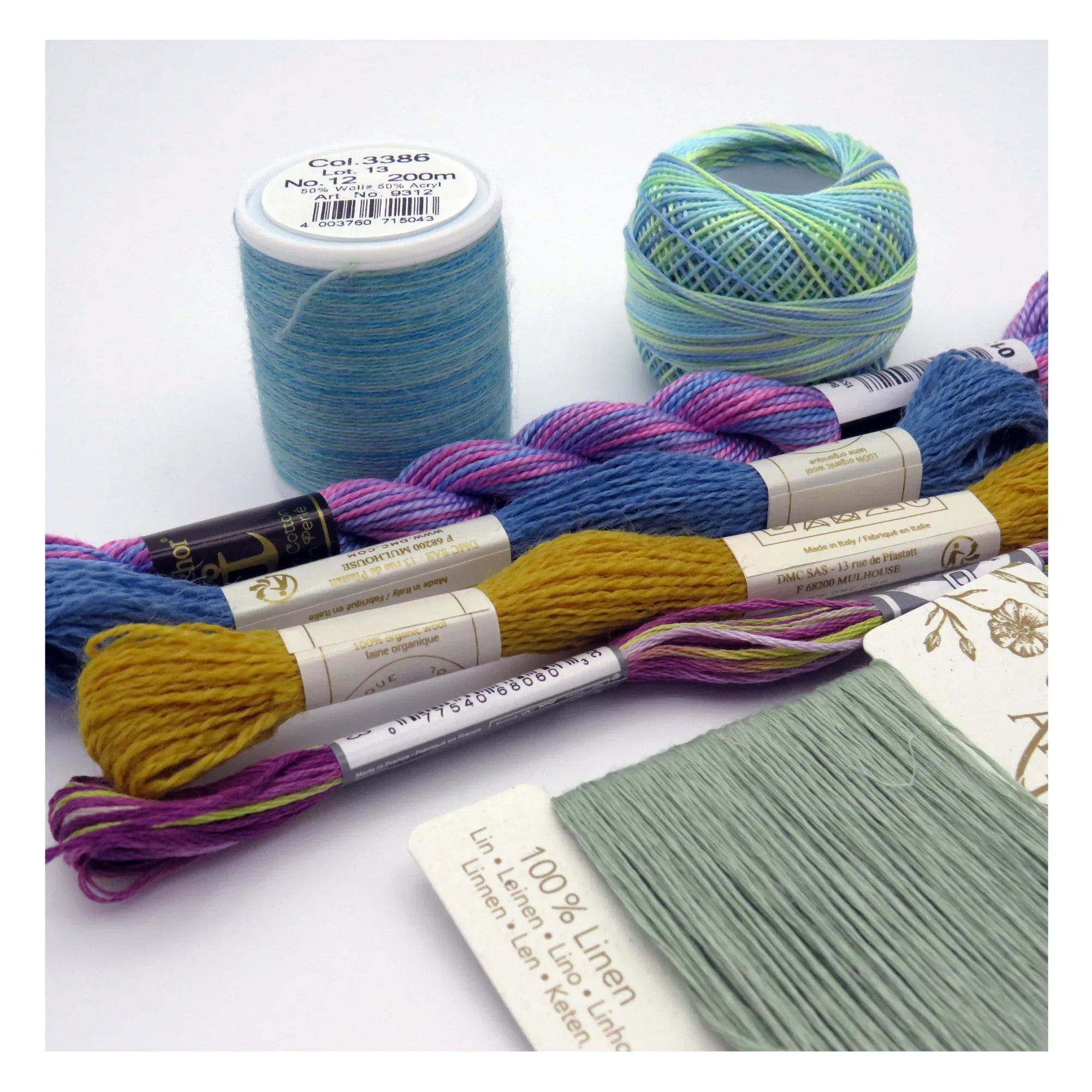 Collection of embroidery threads and linen fabric on a white background