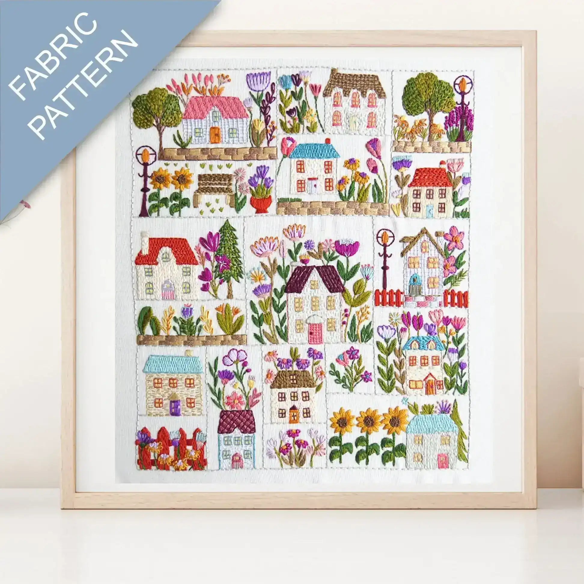 Framed fabric pattern with colorful houses and flowers on a white background