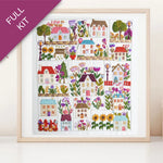 Framed cross-stitch pattern with colorful houses and flowers on a white background