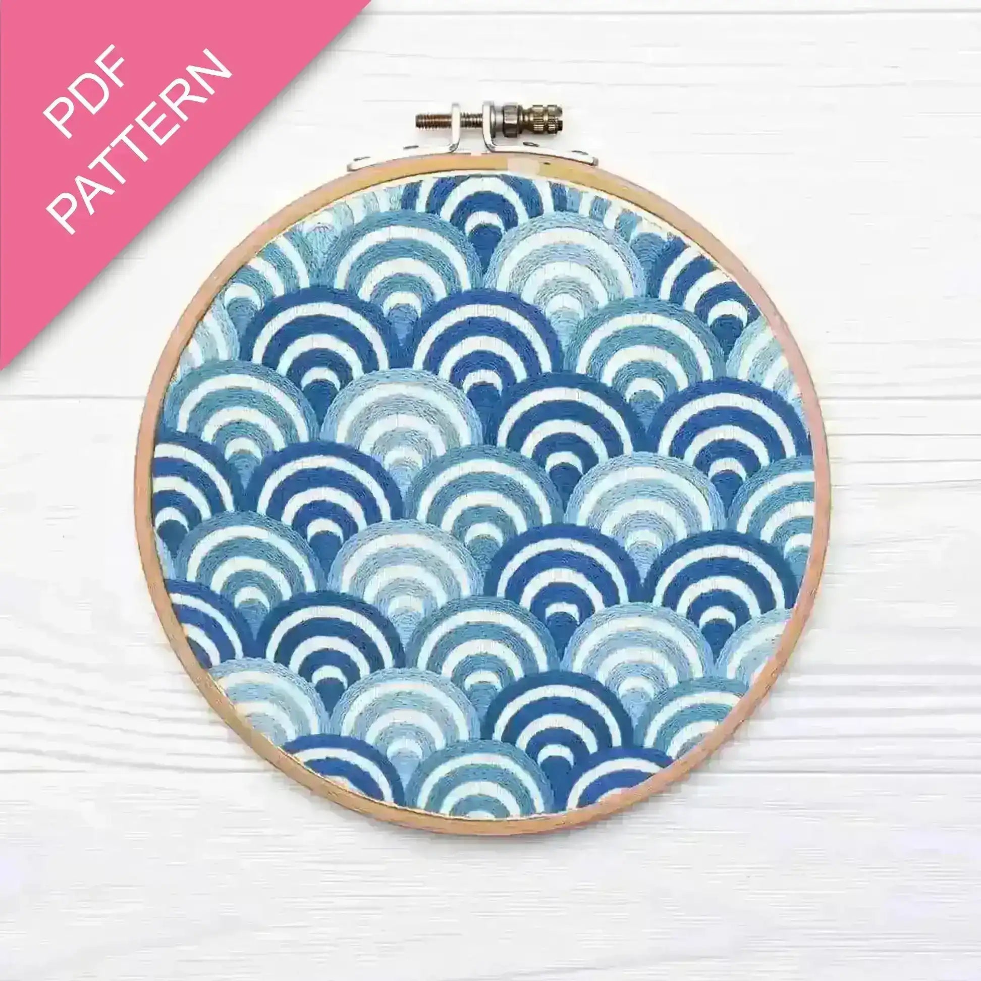 Embroidery hoop with blue and white wave pattern on a white background