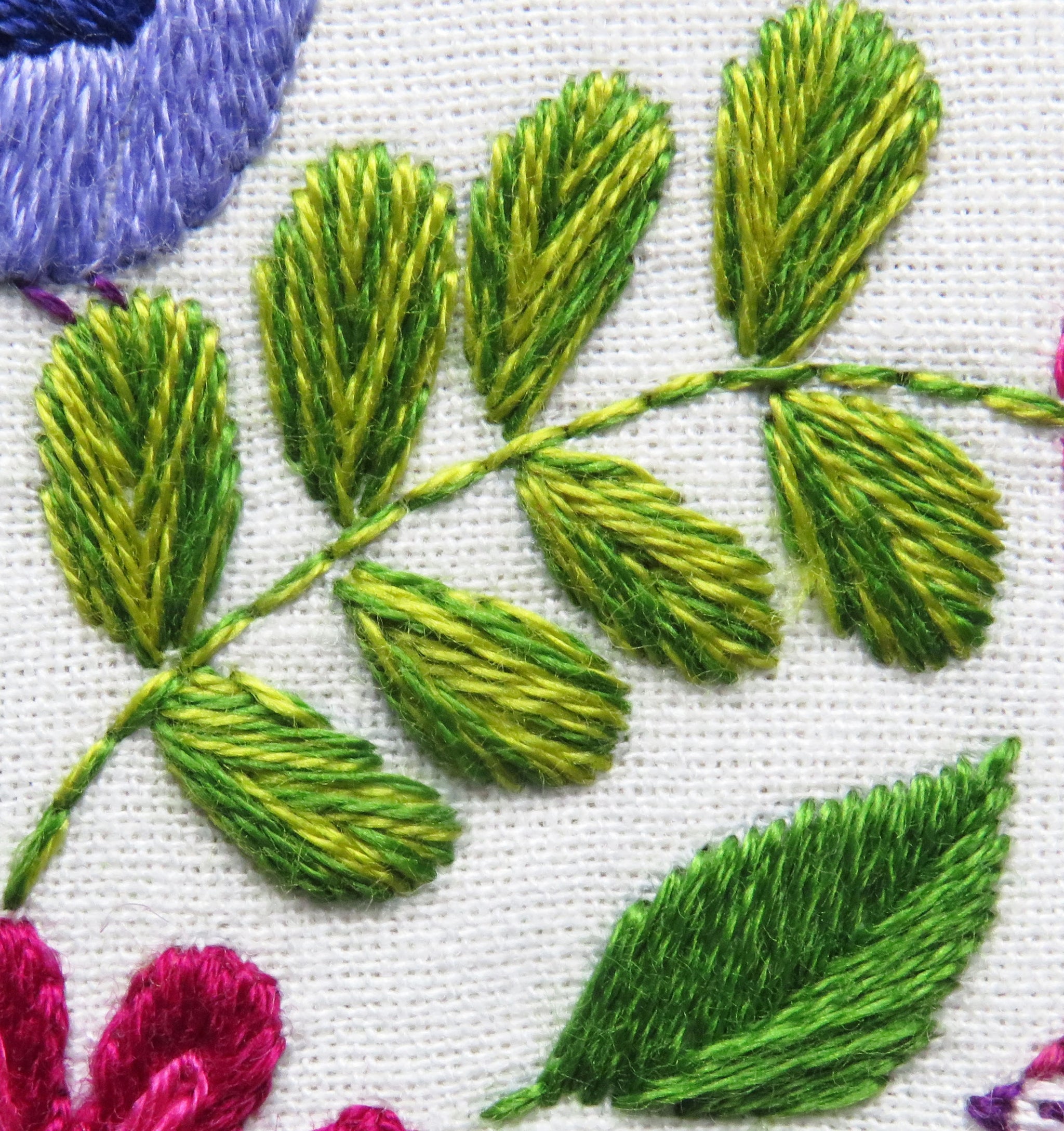 Close-up of embroidered green leaves on a white fabric background