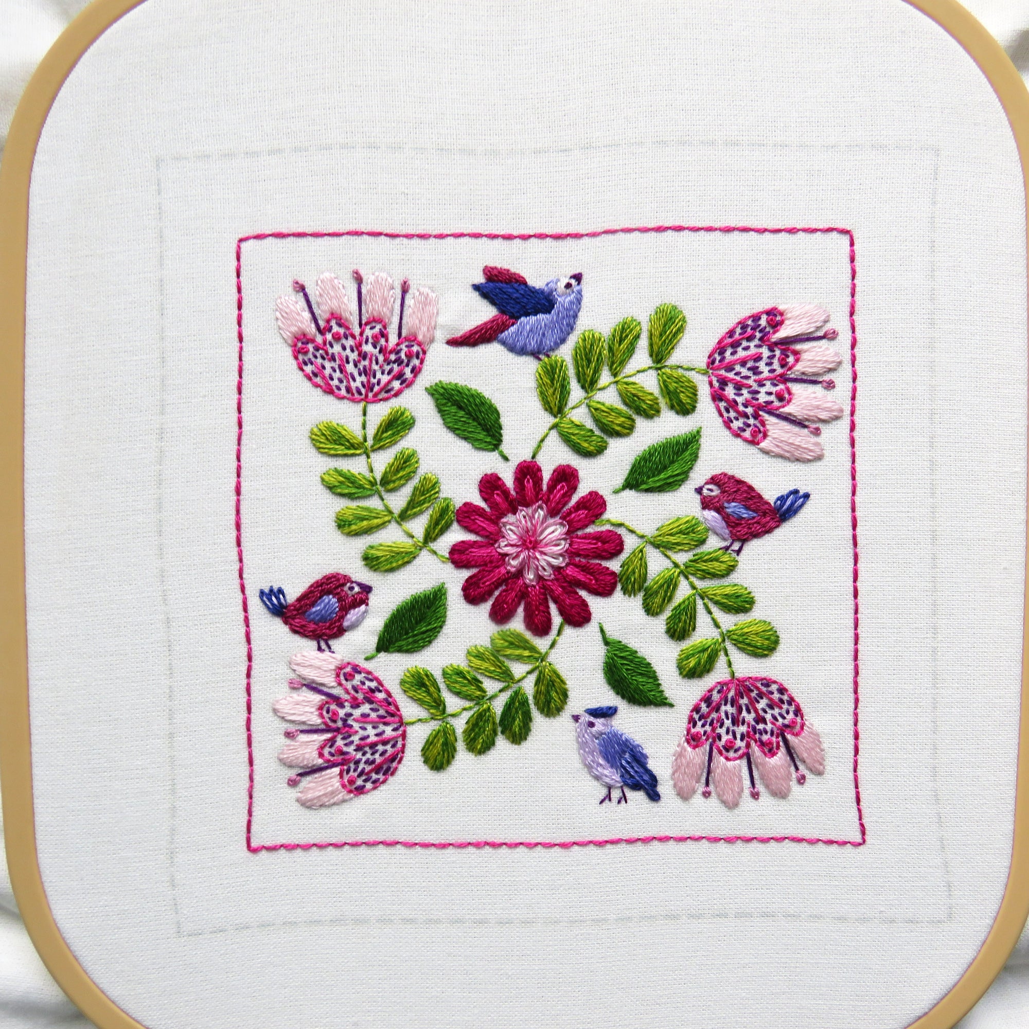 Embroidery hoop with floral and bird design on a white background