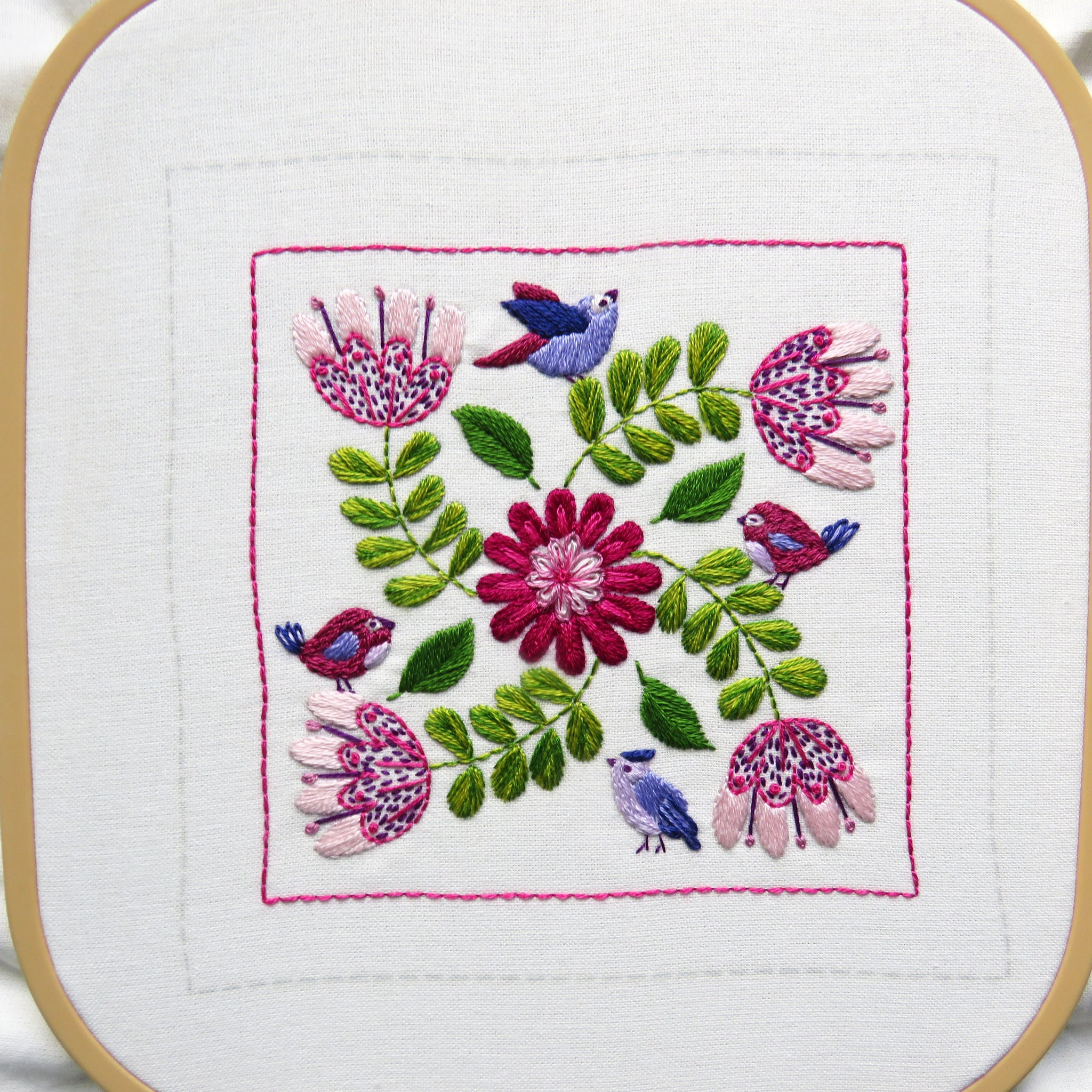 Embroidery hoop with floral and bird design on a white background