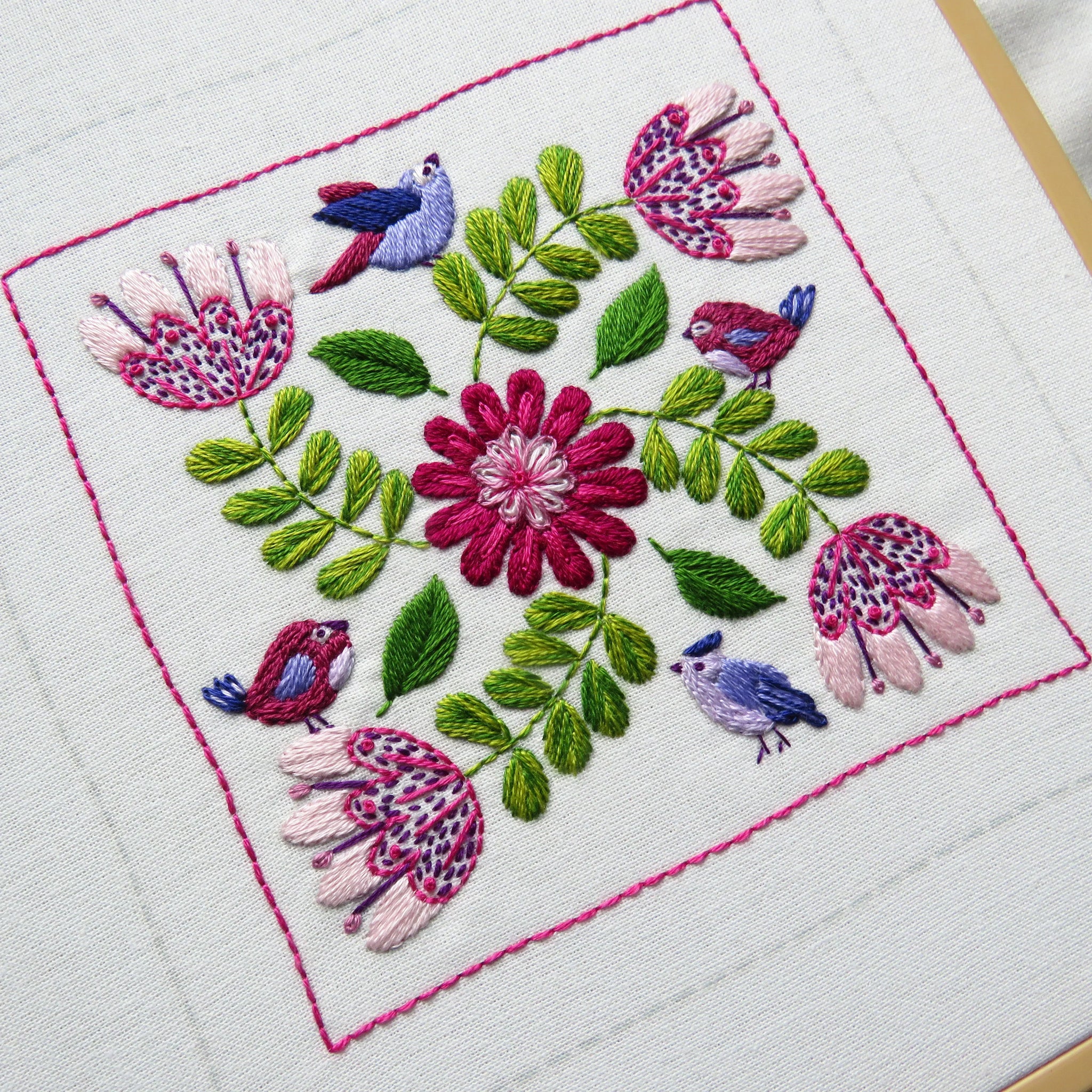 Embroidered design with flowers and birds on a white fabric background