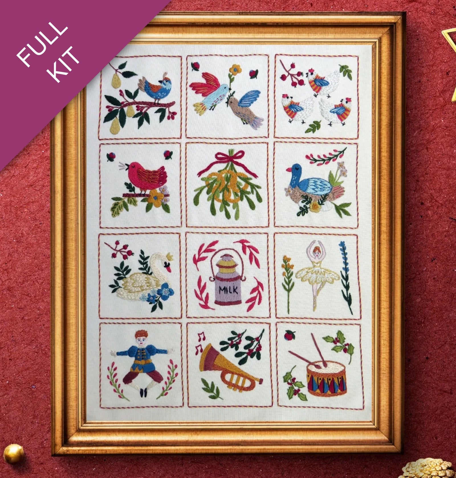 Framed cross-stitched sampler with various designs on a red background