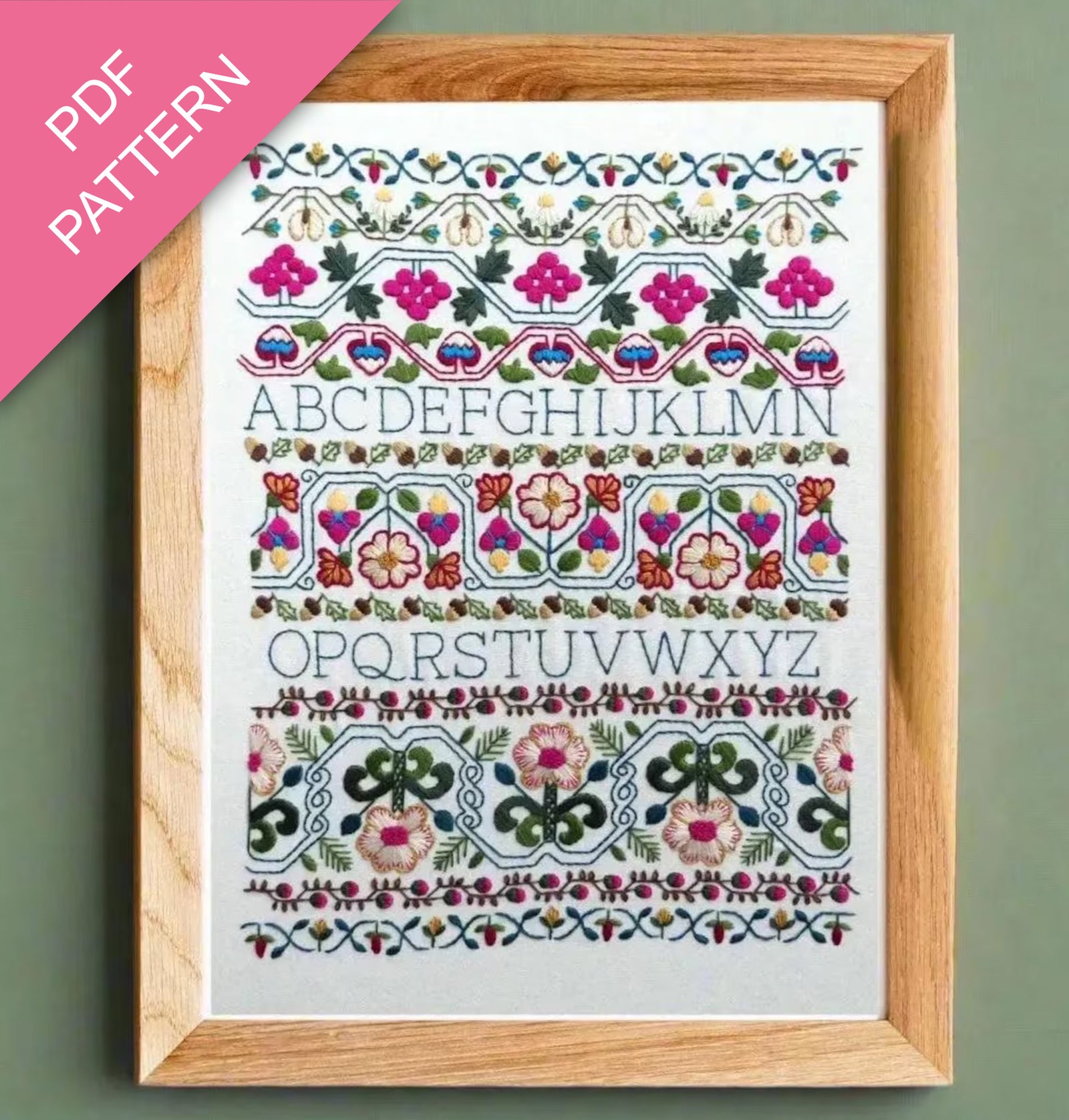 Embroidery pattern with floral designs and letters framed on a green background