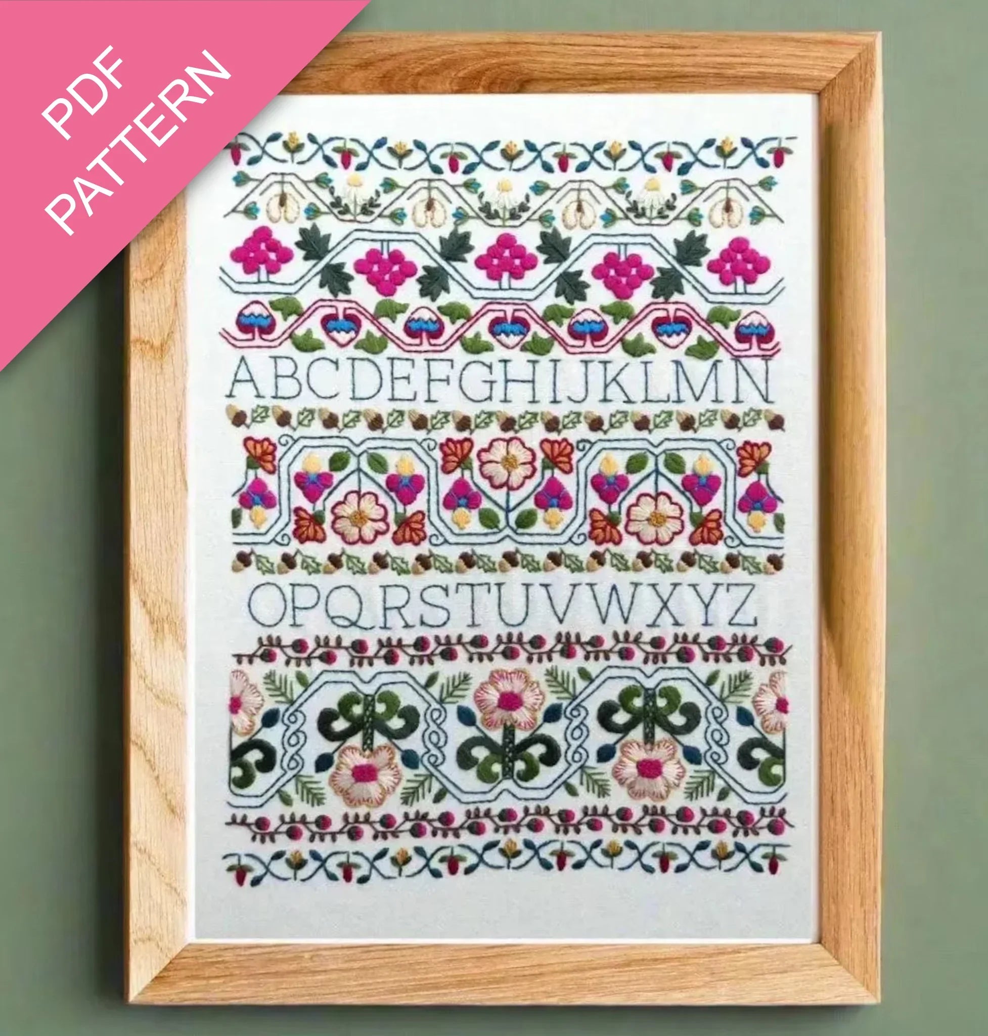 Embroidery pattern with floral designs and letters framed on a green background