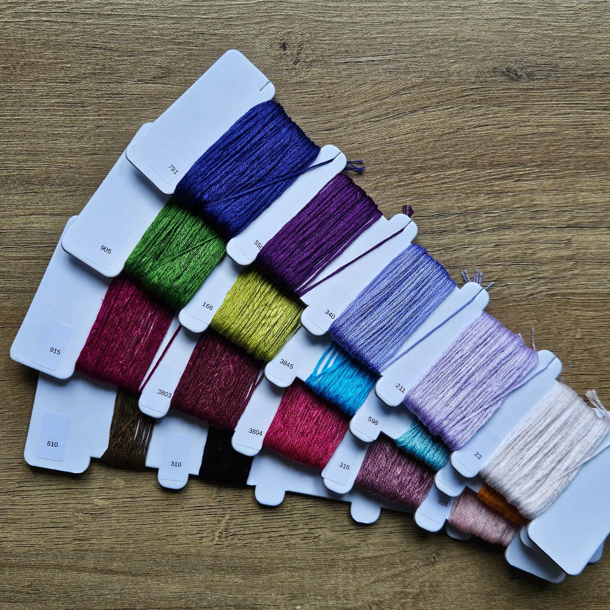 Assorted spools of thread in various colors on a wooden surface