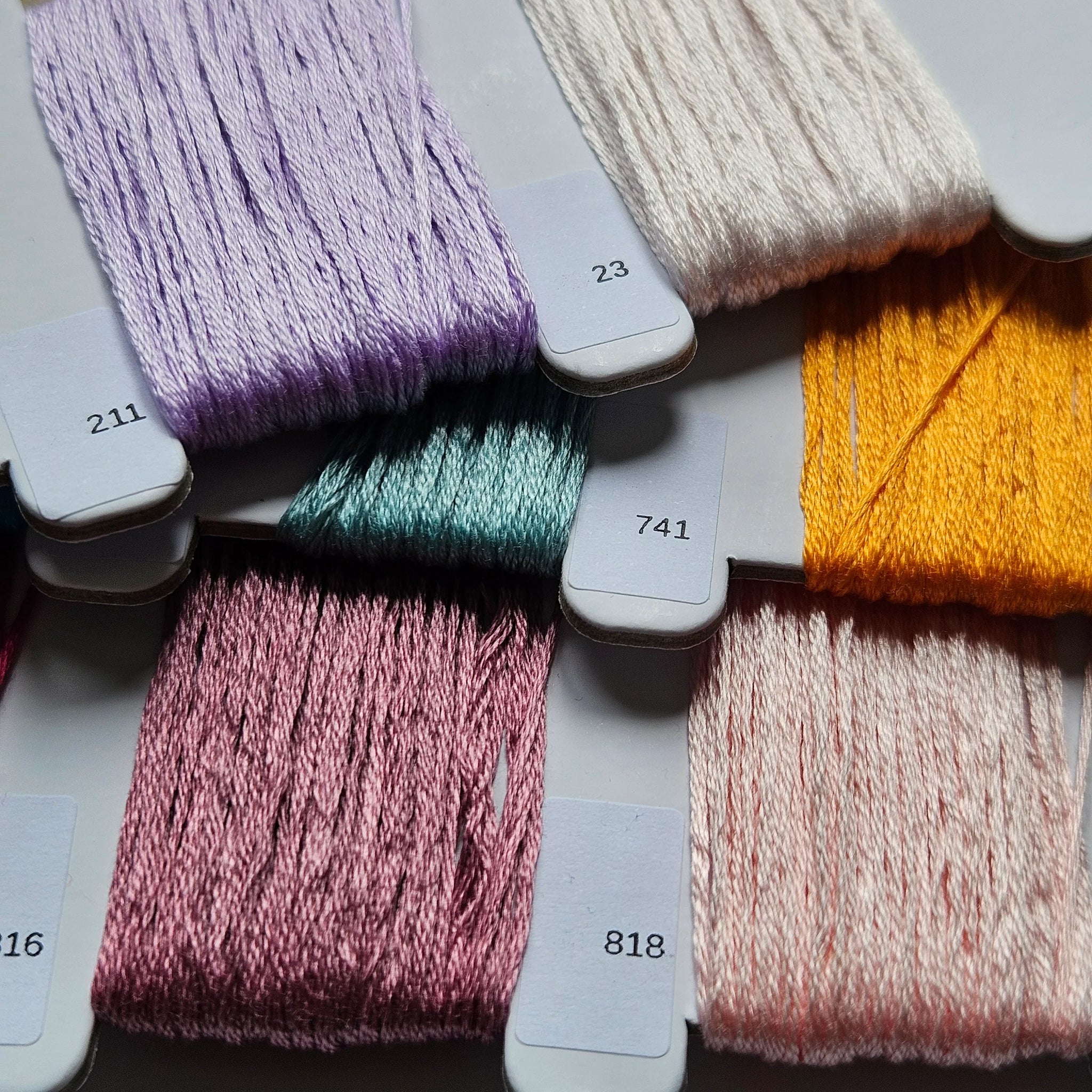 Collection of colorful yarn skeins with labels on a gray surface