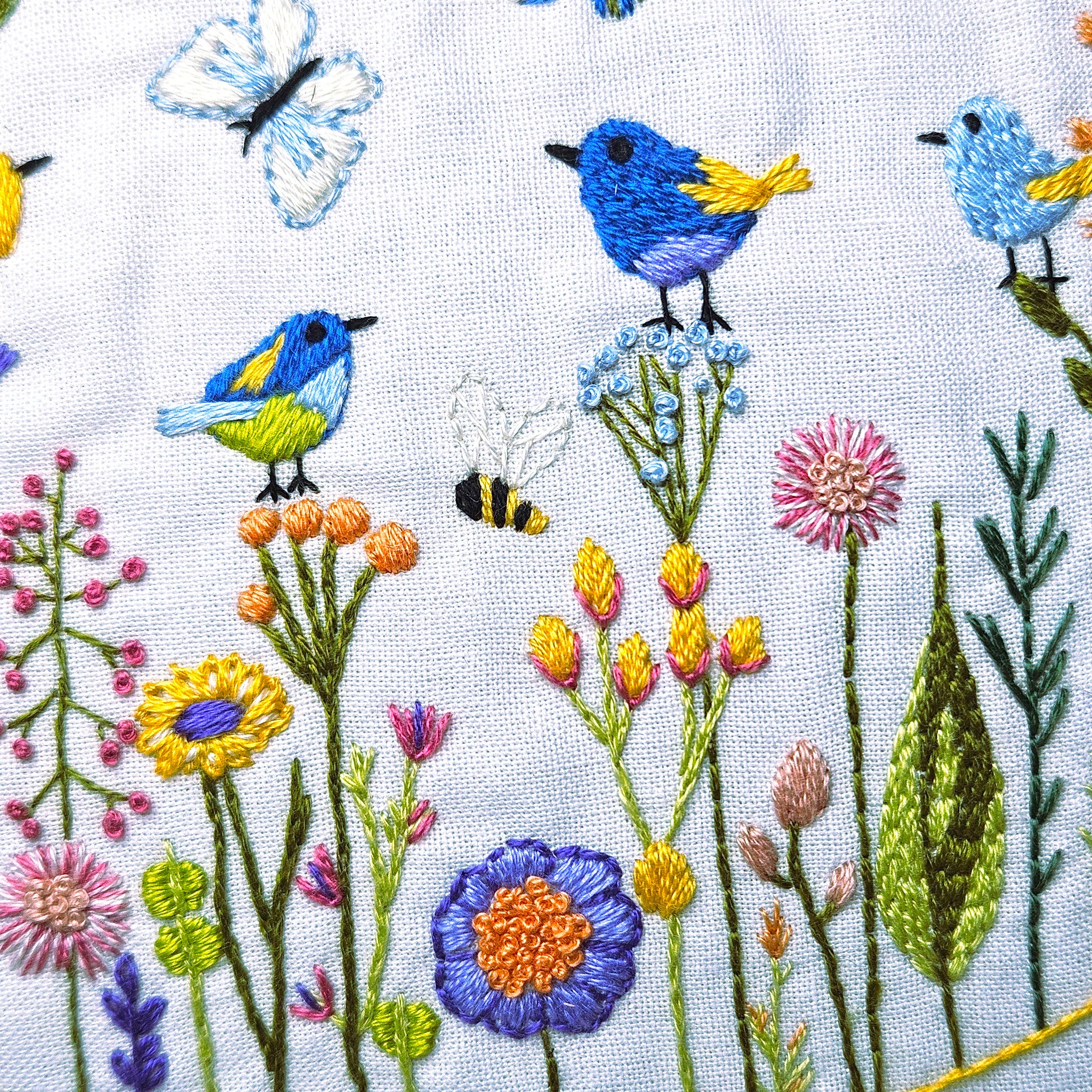 Embroidered design of birds, flowers, and butterflies on fabric