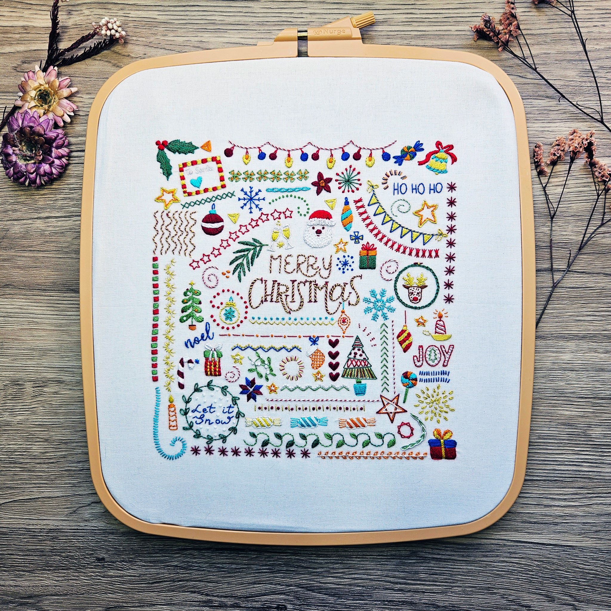 Embroidery hoop with Christmas-themed cross-stitch on a wooden surface