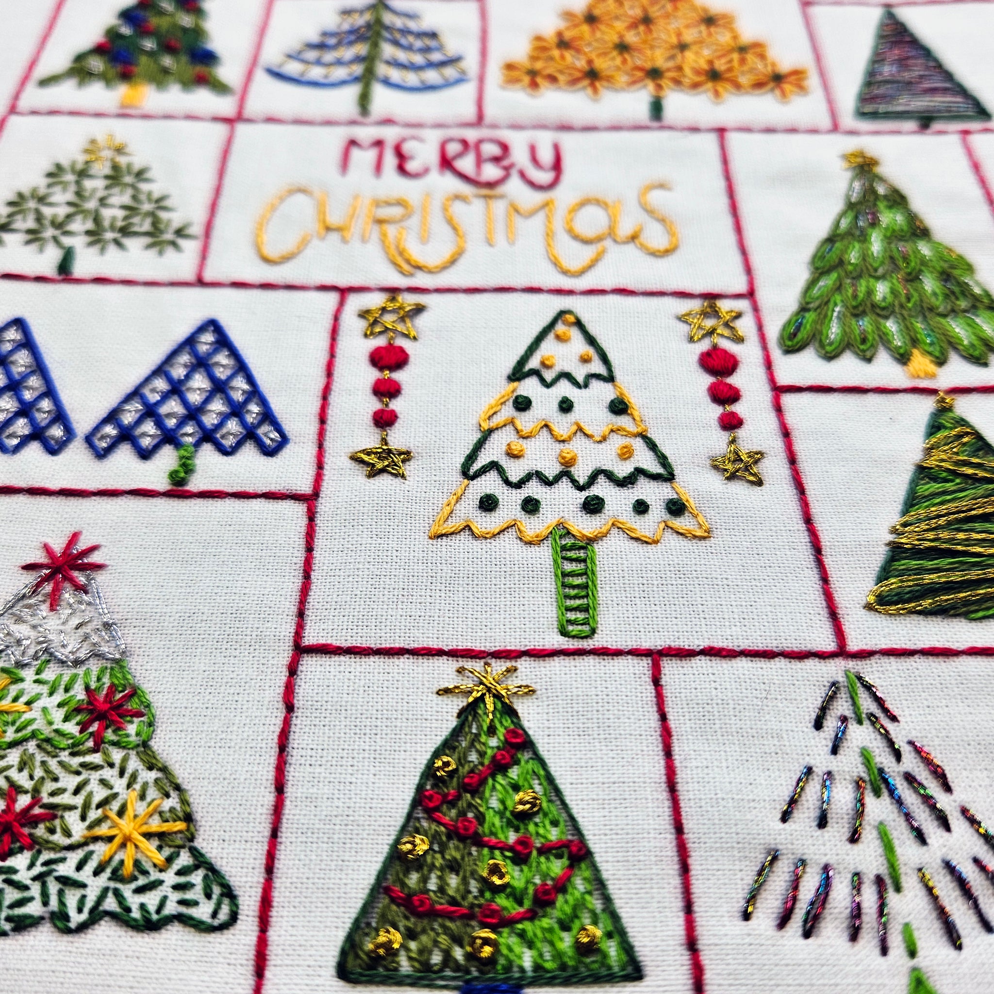 Embroidered Christmas trees and 'Merry Christmas' text on a quilted fabric background.