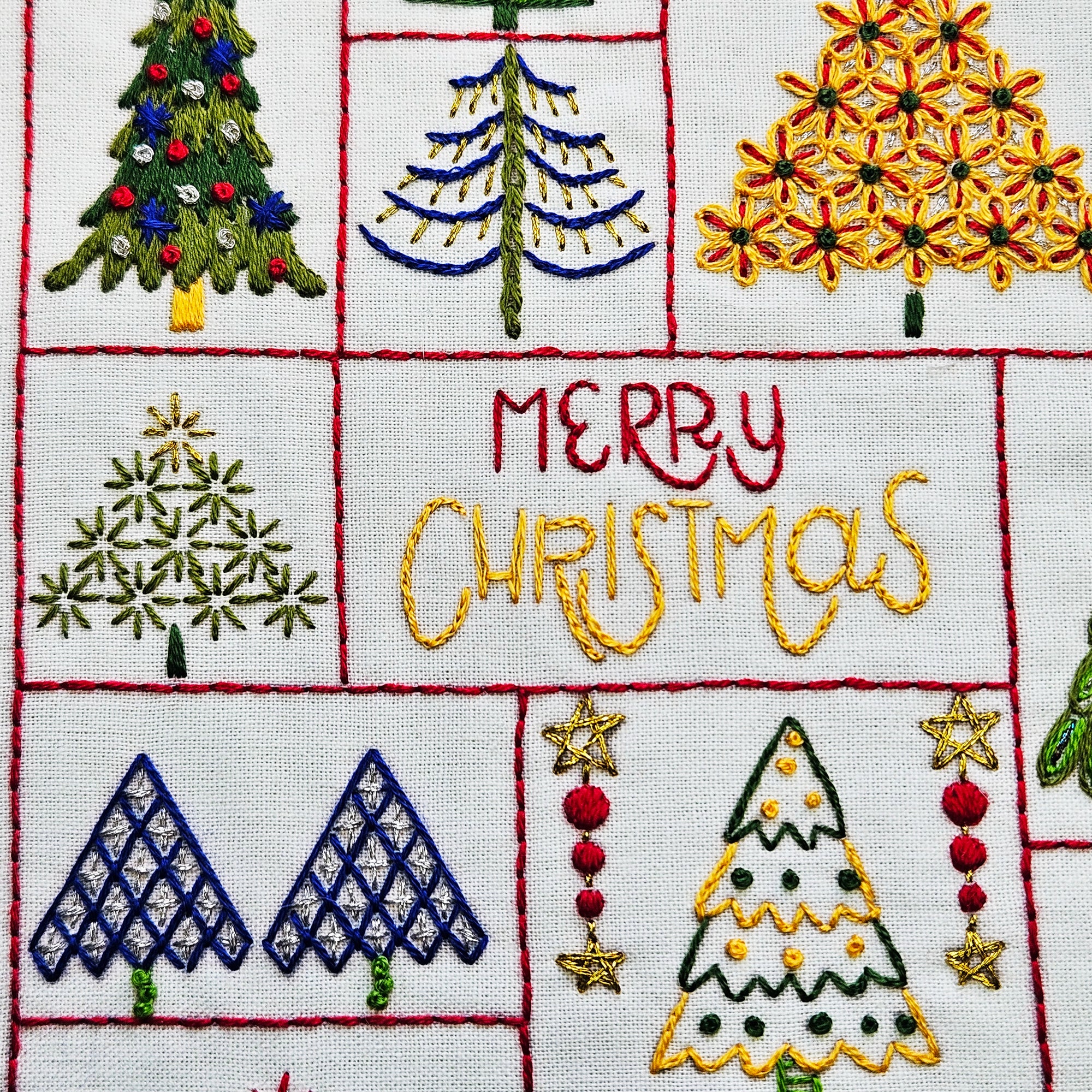 Embroidered Christmas-themed fabric with trees and 'Merry Christmas' text.