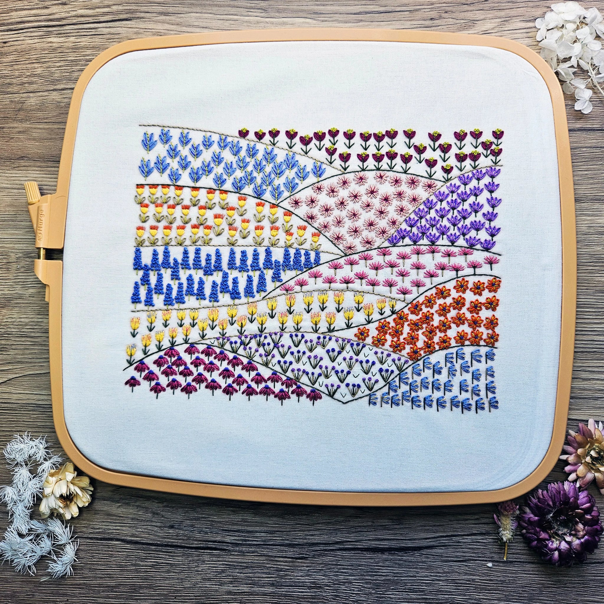 Embroidery hoop with a colorful floral pattern on a wooden surface.