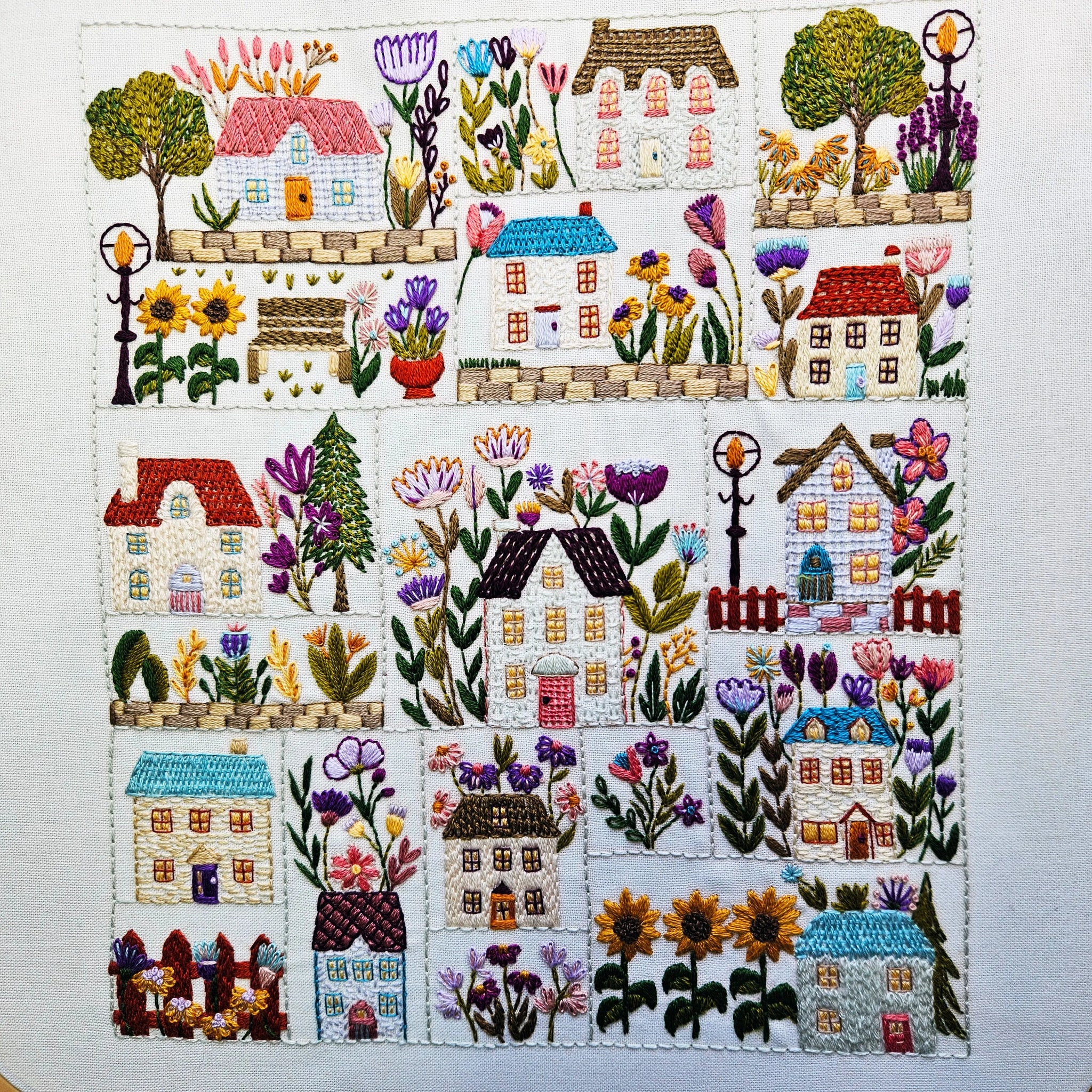 Embroidered panel with houses and flowers on a white background