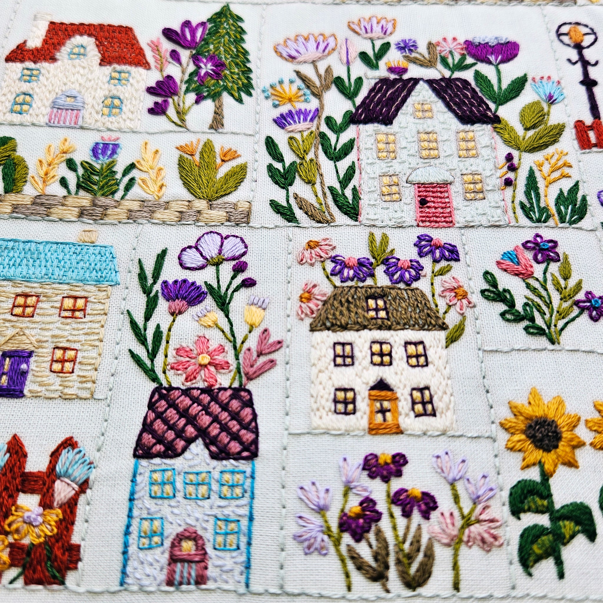 Embroidered patchwork with houses and flowers on a white background