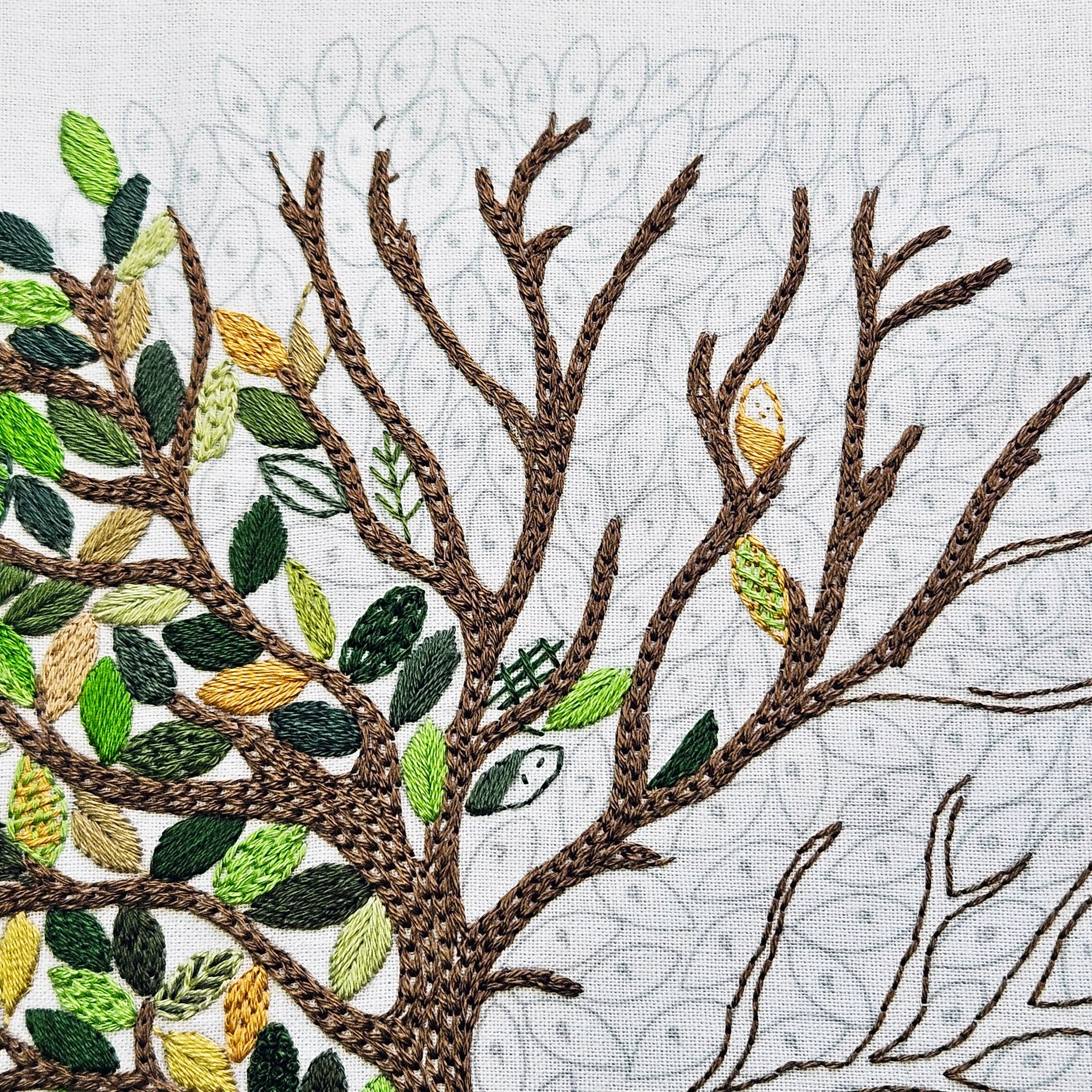 Embroidered tree design with leaves on a textured fabric background