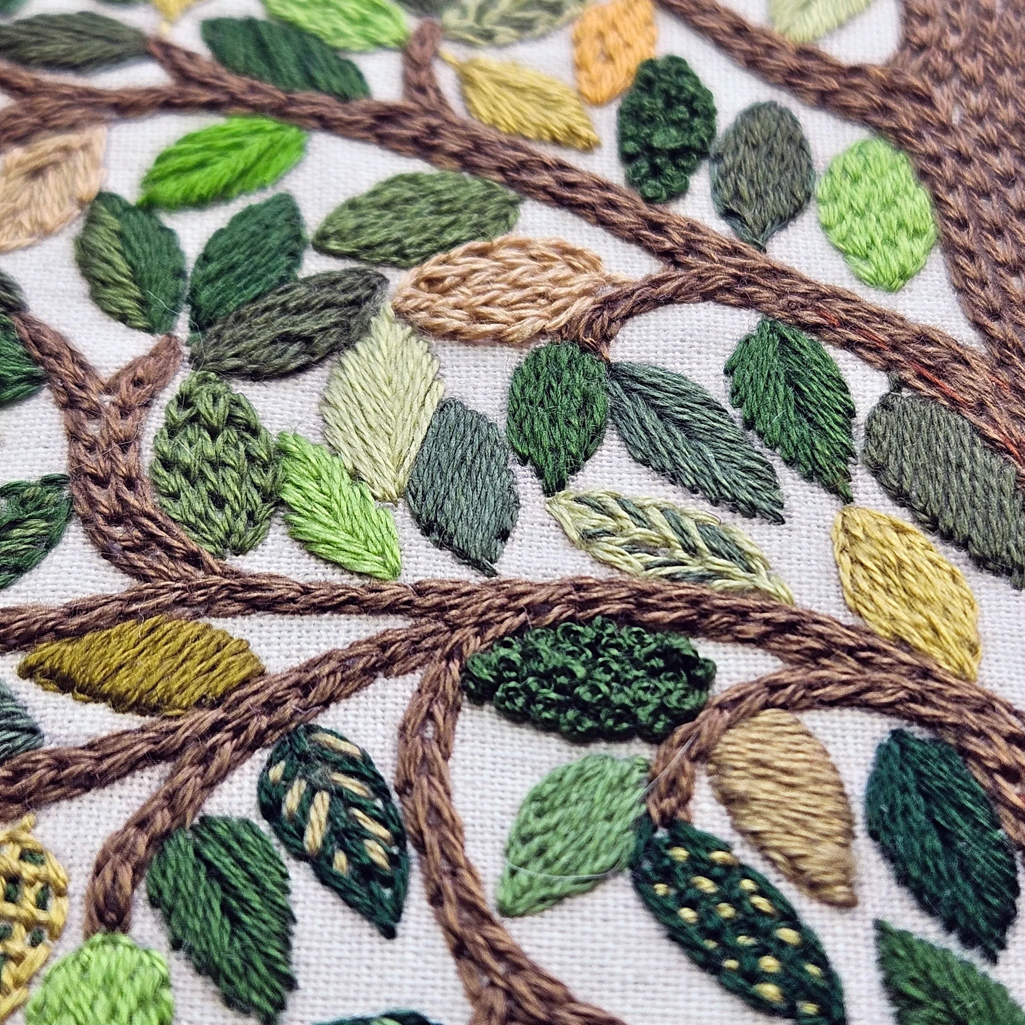 Close-up of embroidered leaves and branches on fabric